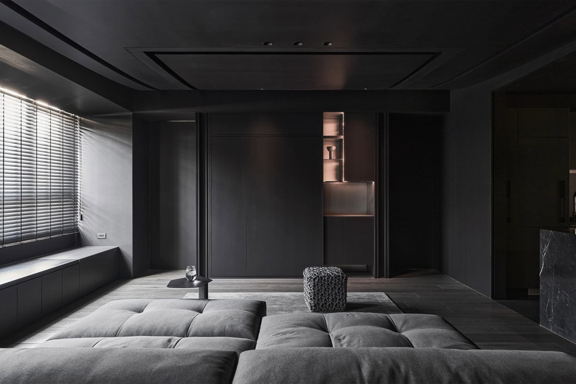 Modern minimalist living room with dark wood accents and leather seating, featuring dark metallic elements and a sleek, moder