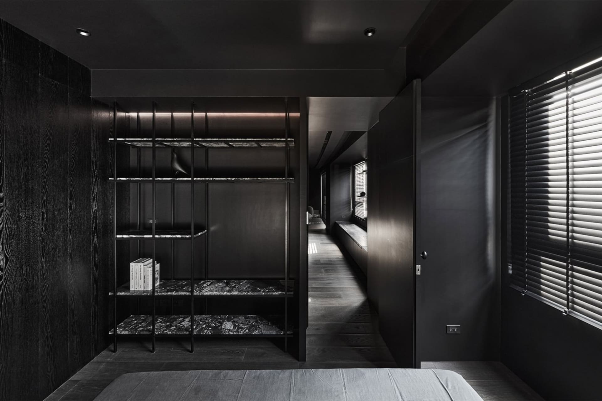 A modern bedroom featuring a black bookshelf made of metal, marble, and wood.