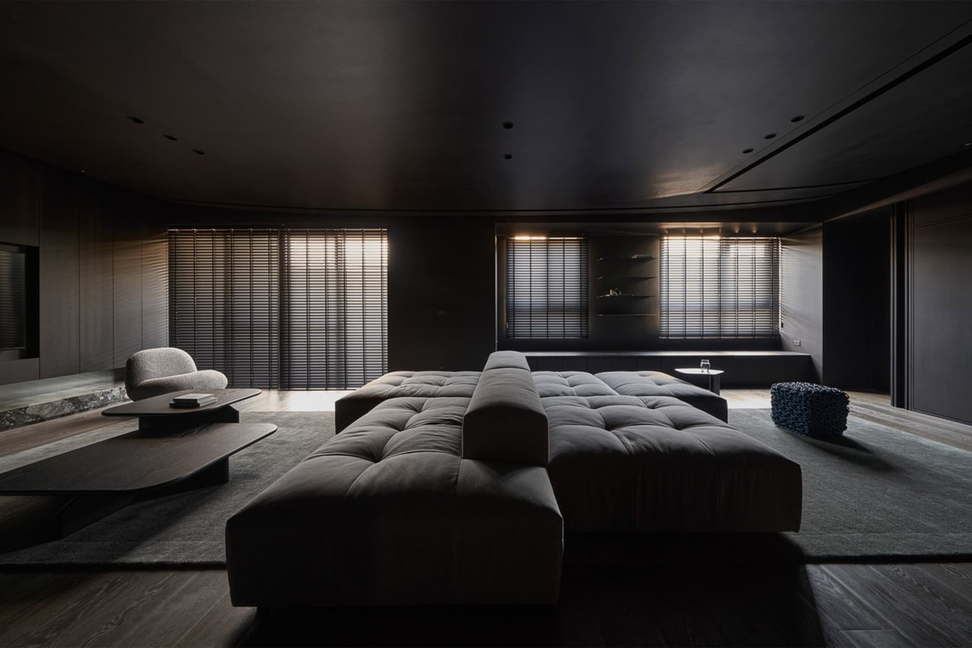 A modern living room with a large grey fabric couch, wooden coffee table, and dark wooden floor.