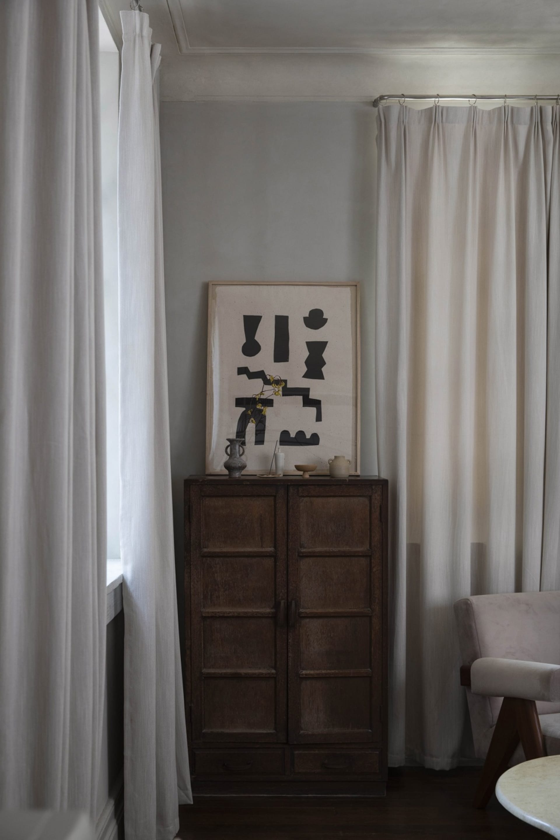 Minimalist living room featuring neutral textiles and a wooden cabinet.