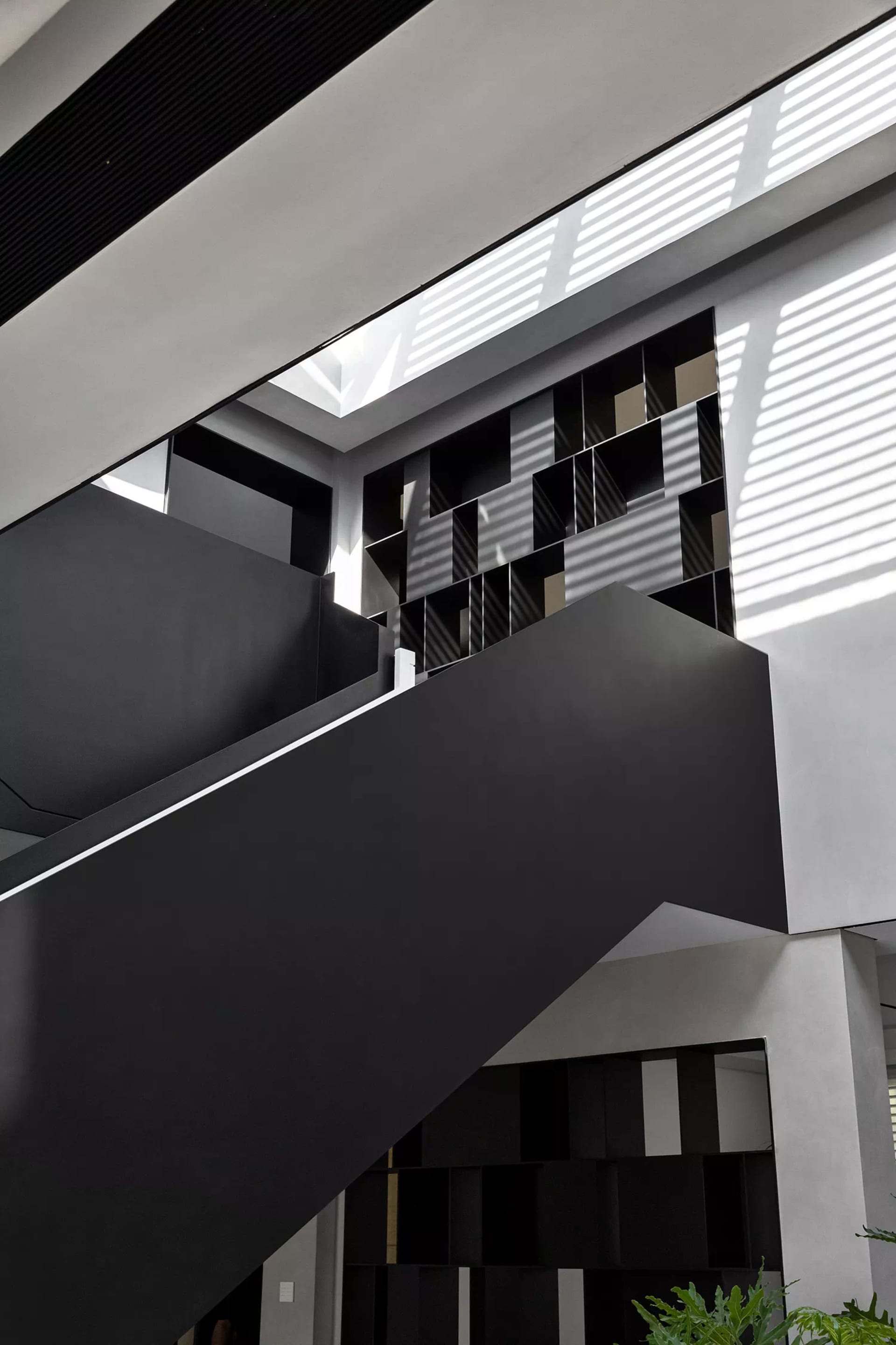 Modern interior design featuring matte black stairs and geometric concrete wall