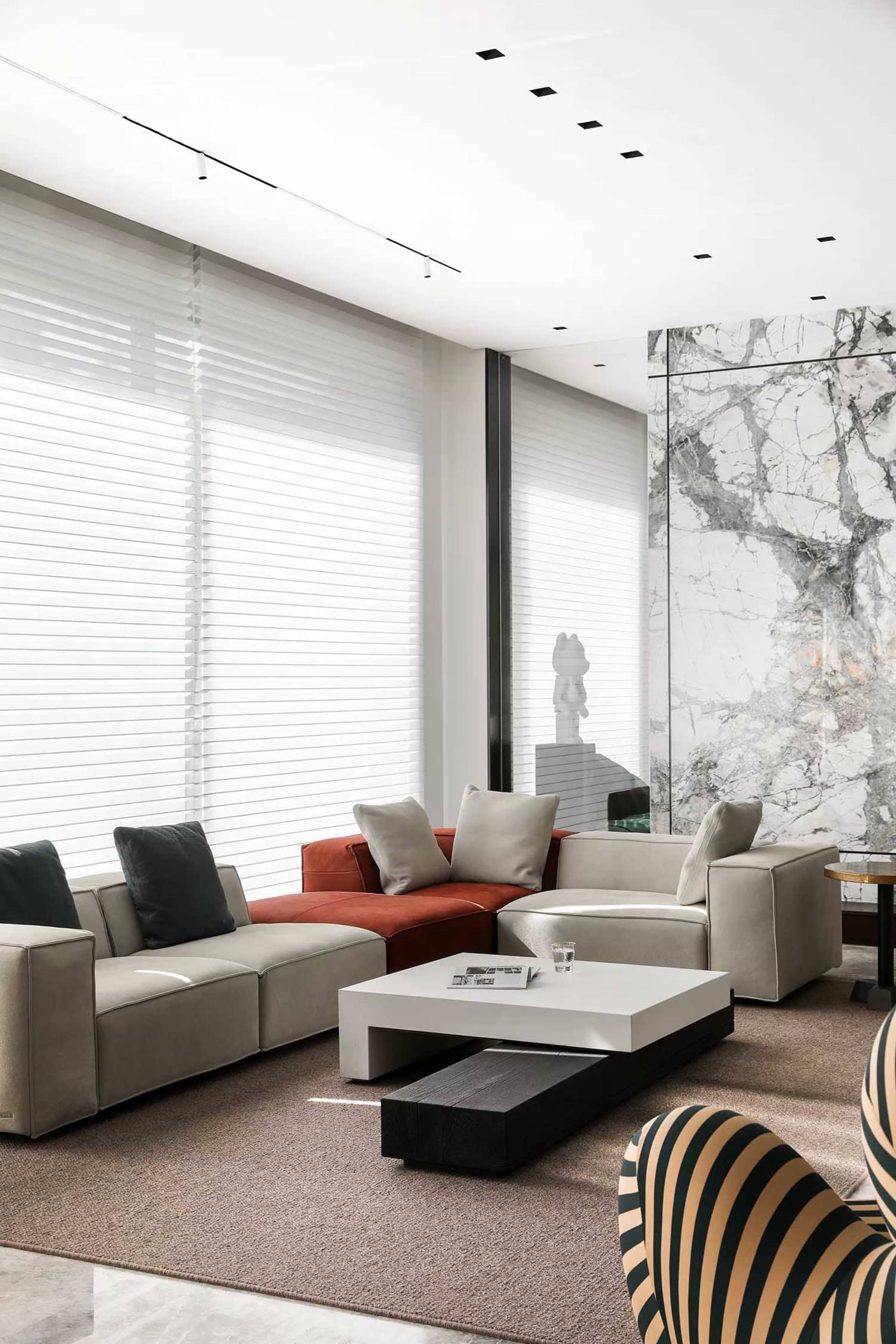 Modern living room with concrete walls, contemporary sofa set, and minimalist decor.
