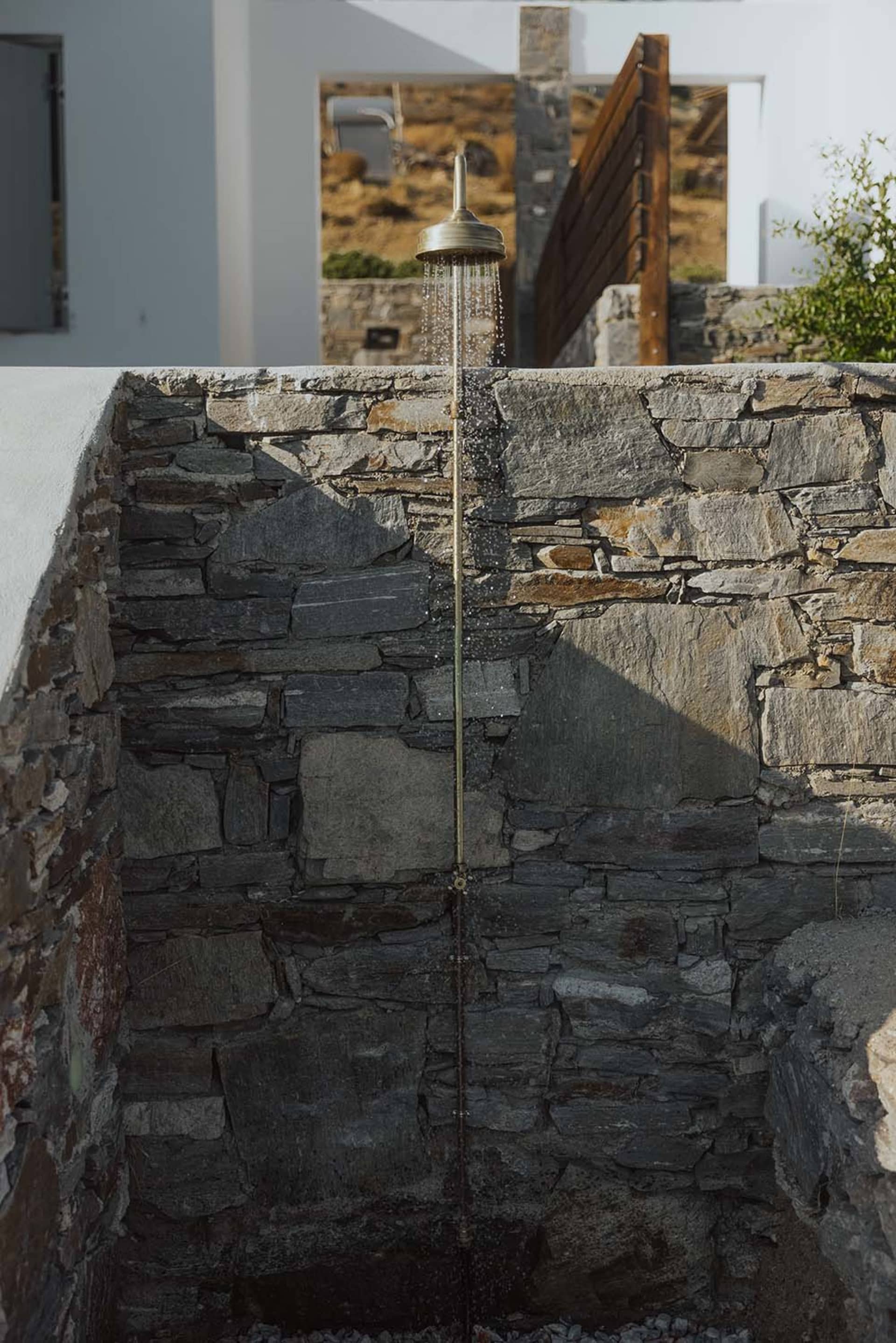 Outdoor shower with stone wall and shower head spraying water