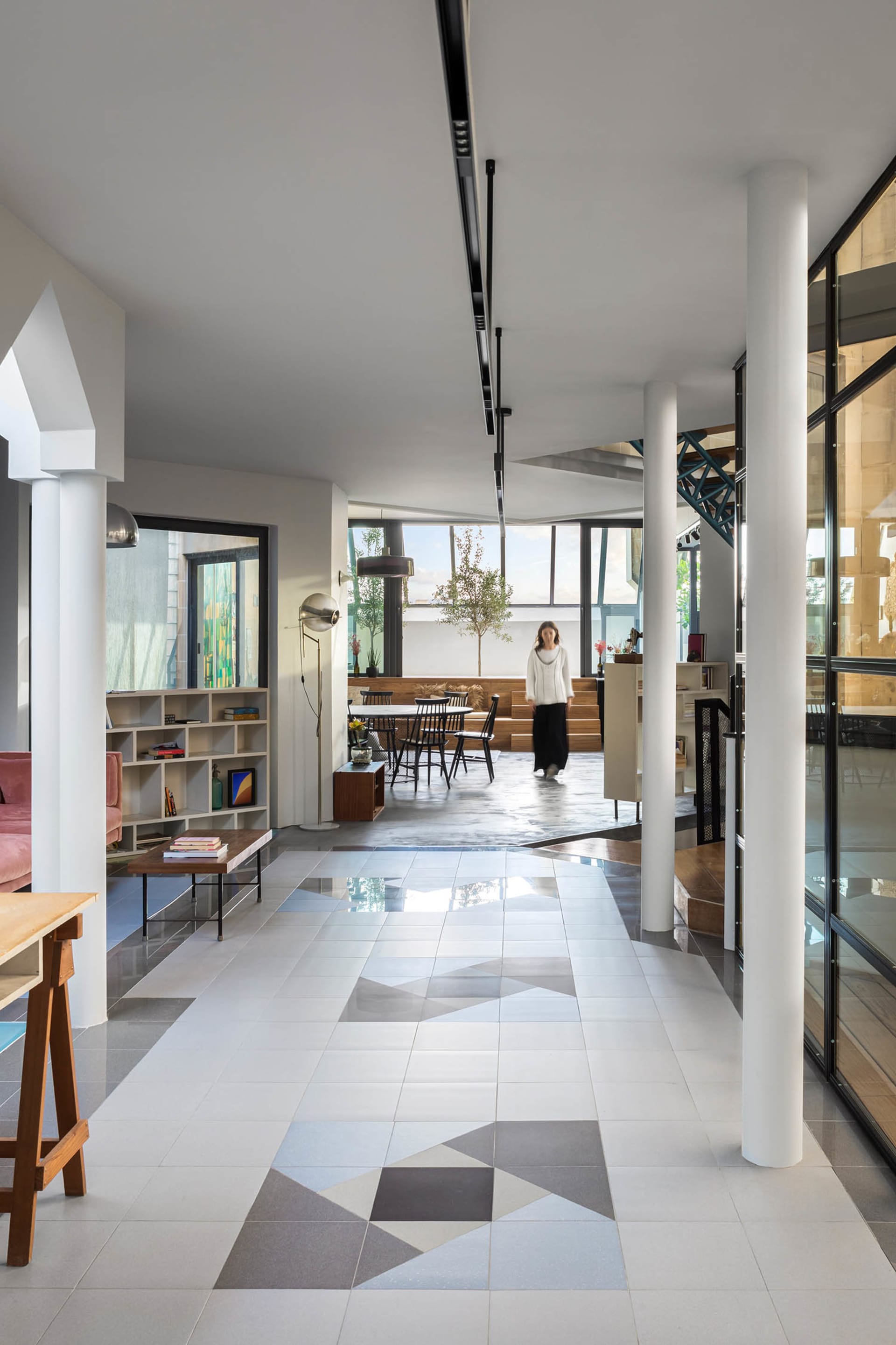 A contemporary living room with concrete floor tiles, industrial-style furniture, and large windows.