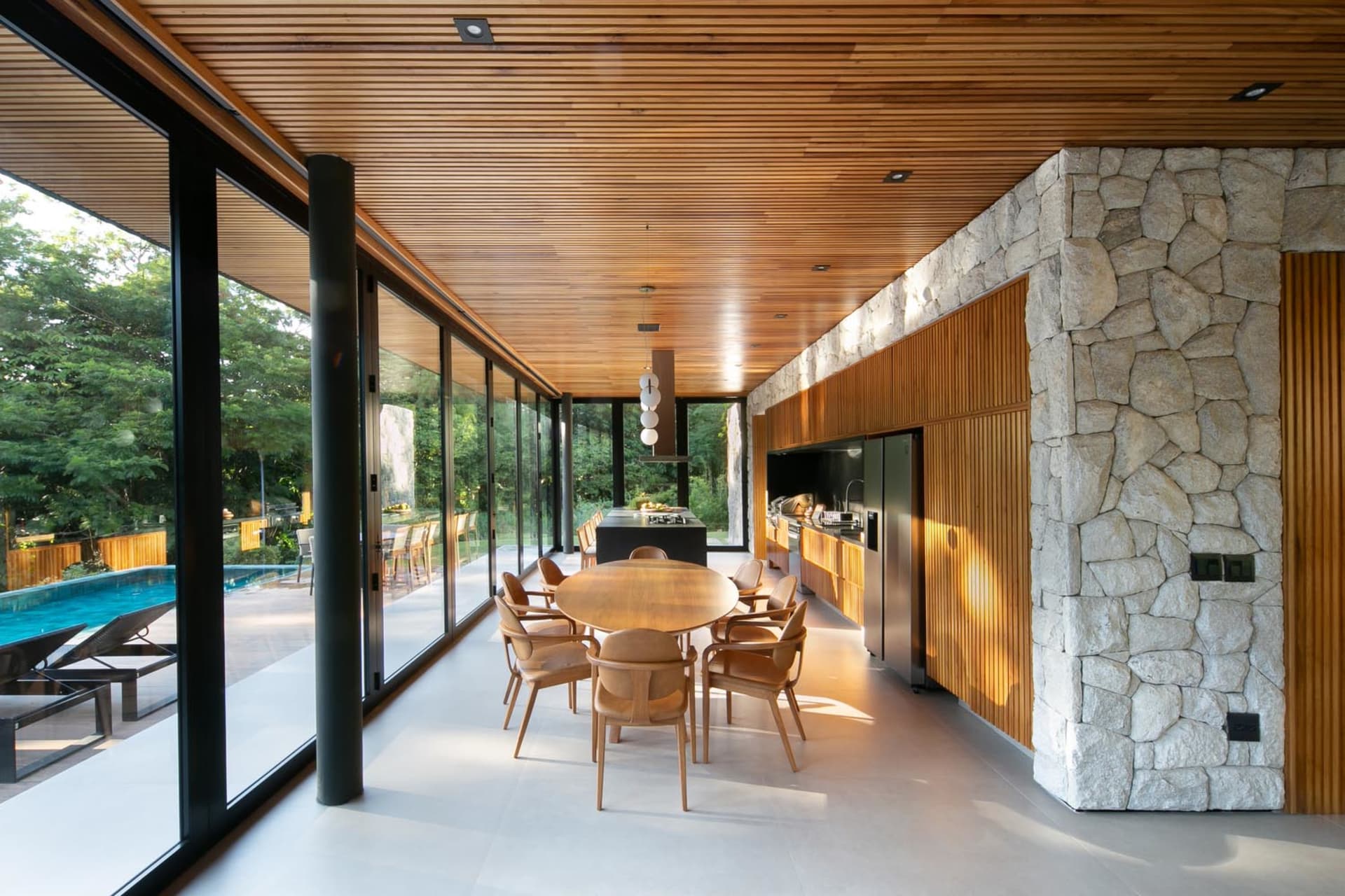 Modern residential kitchen with wood cabinets, stone accents, and glass windows.
