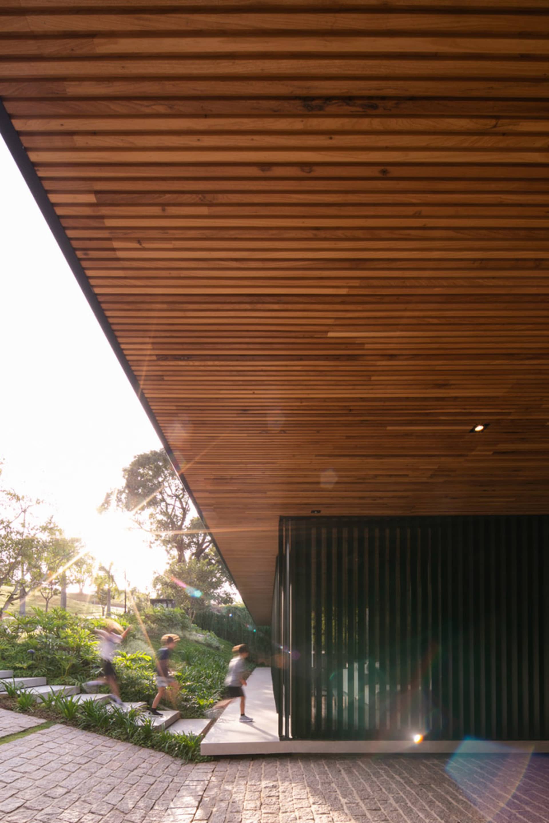 一座現代建築採用木質外觀,搭配斜屋頂與花園區域。