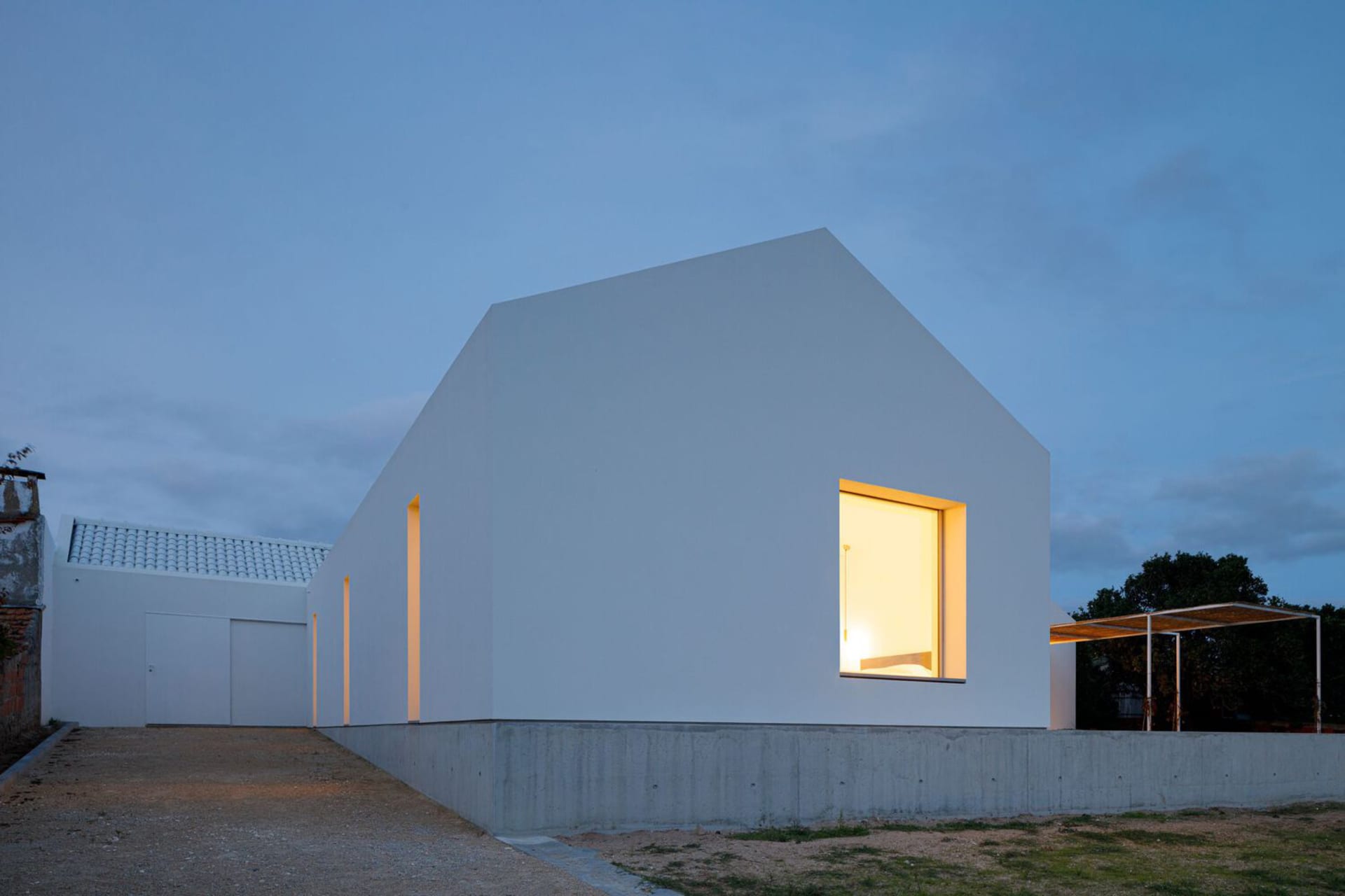 A modern house with a white exterior, featuring concrete and glass materials.