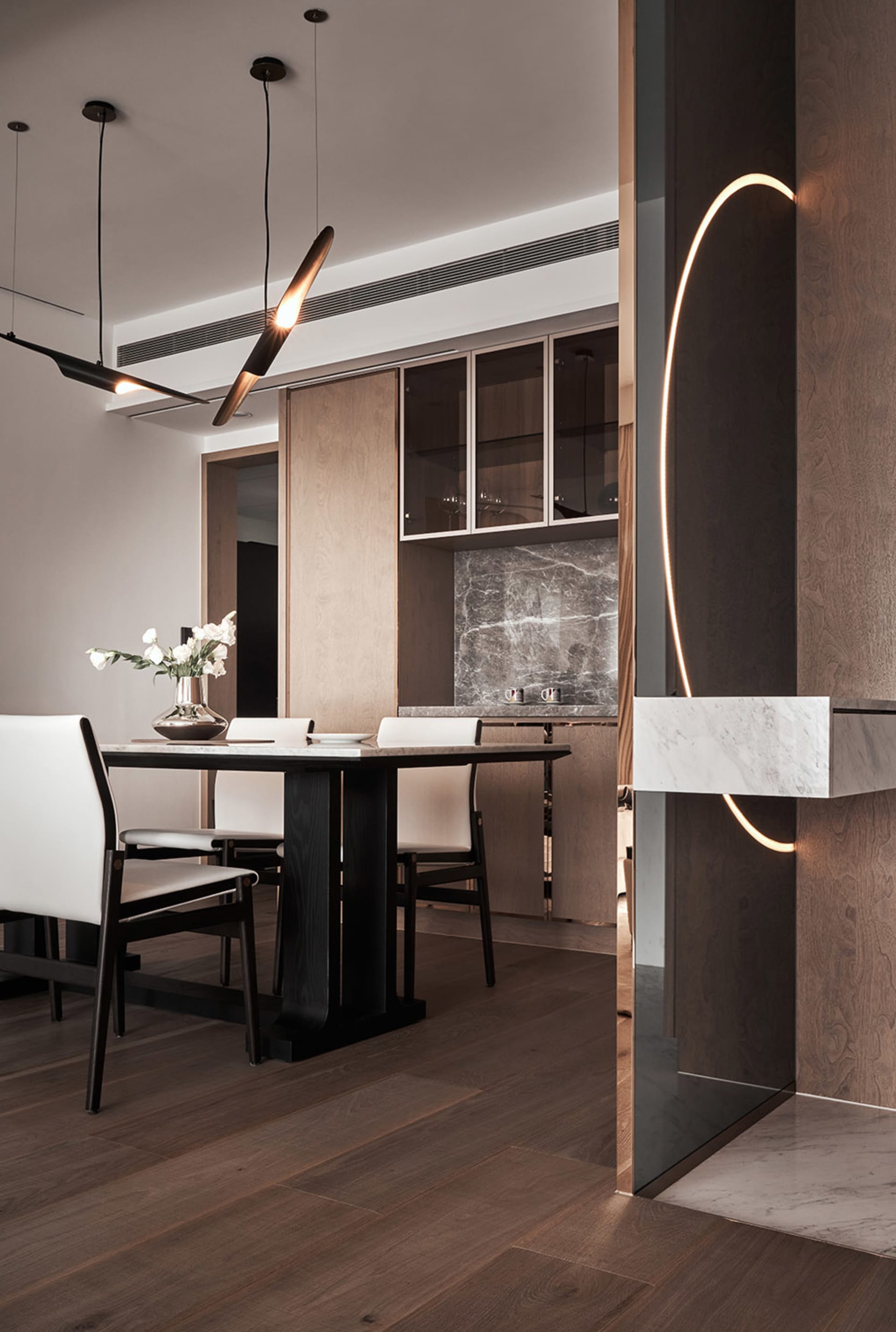 Modern dining room with marble table, wooden chairs, and metal accents