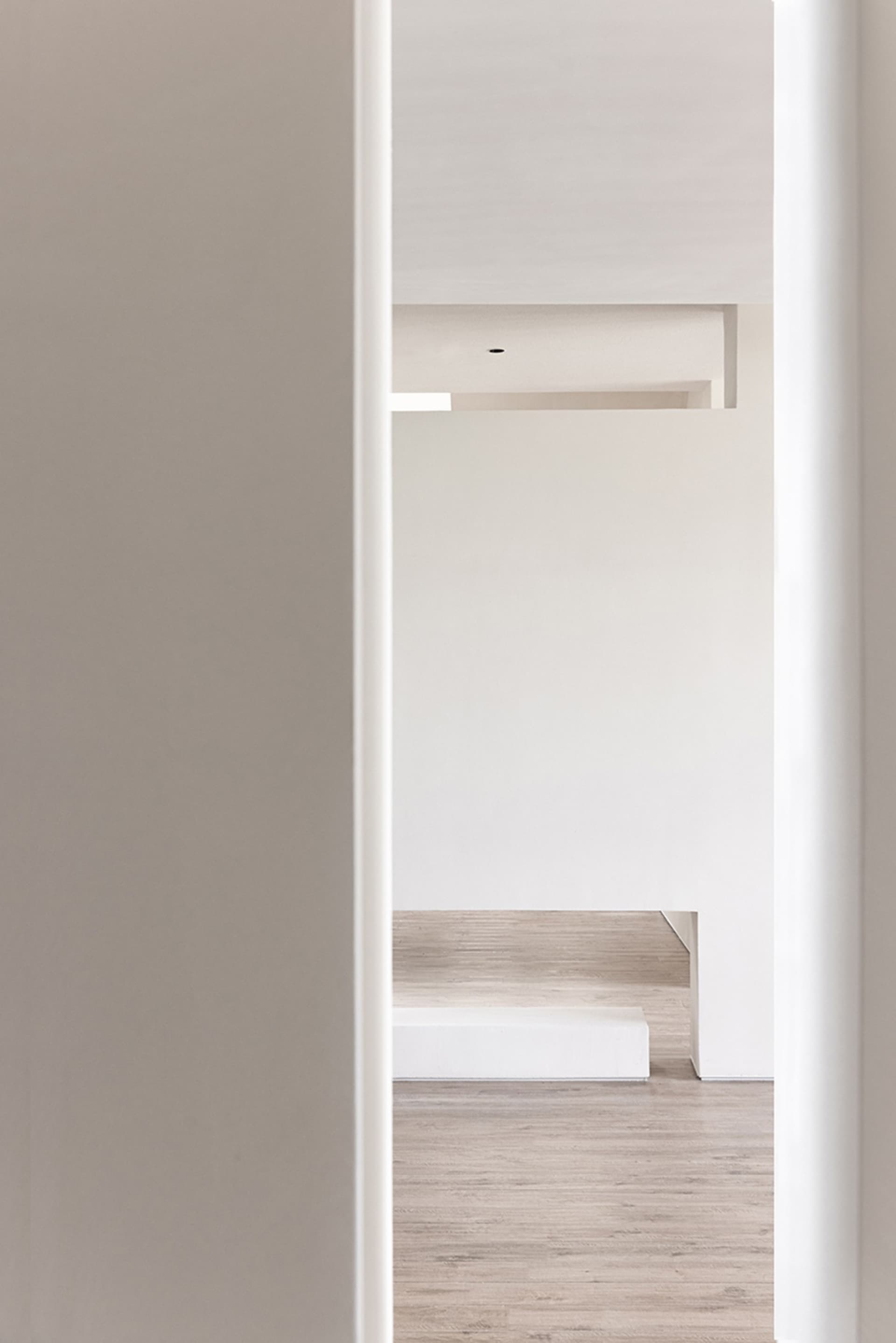 Minimalist modern interior with a white concrete staircase and light wooden flooring.