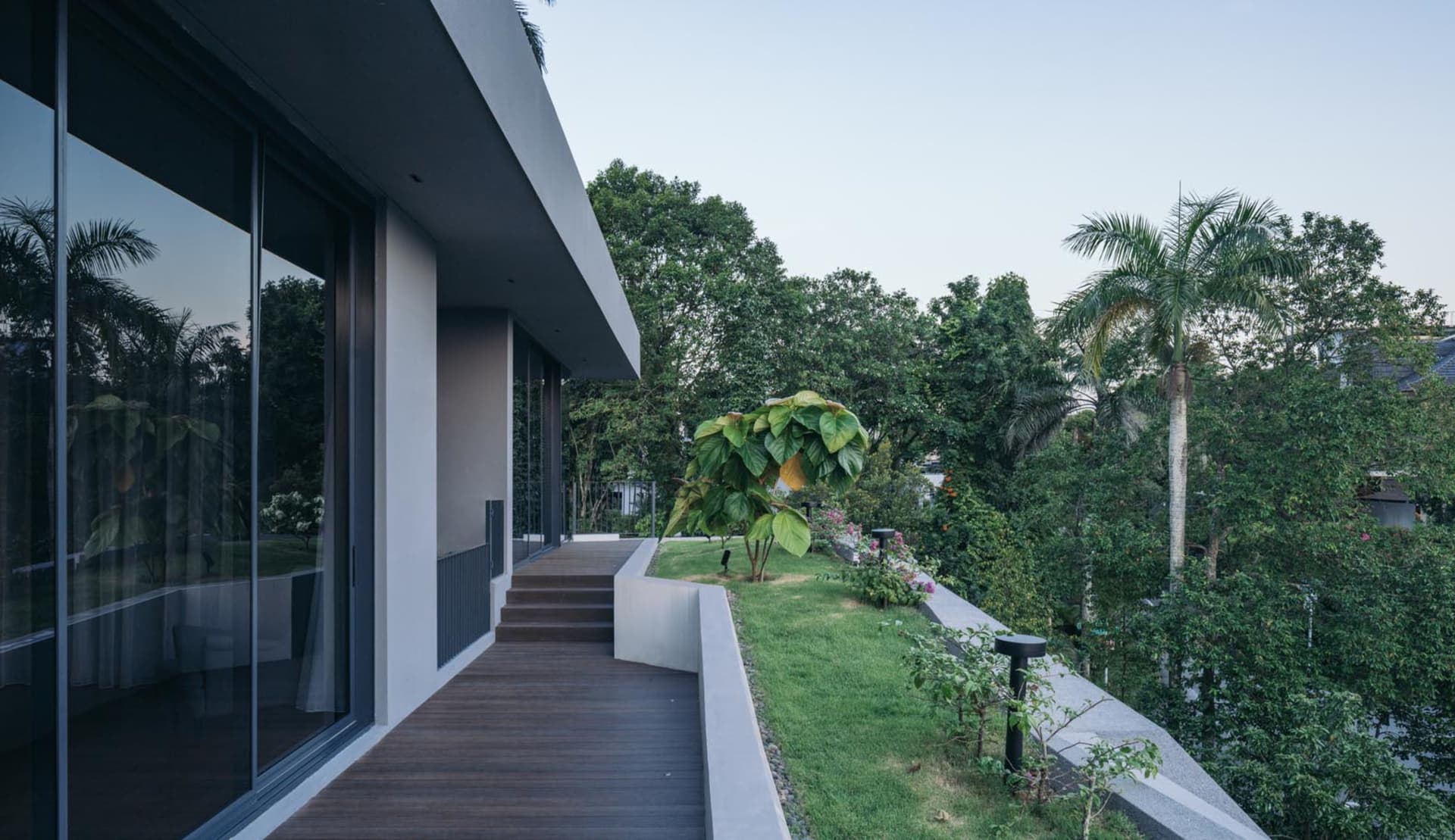 A modern residential exterior featuring a combination of wood, concrete, and greenery.