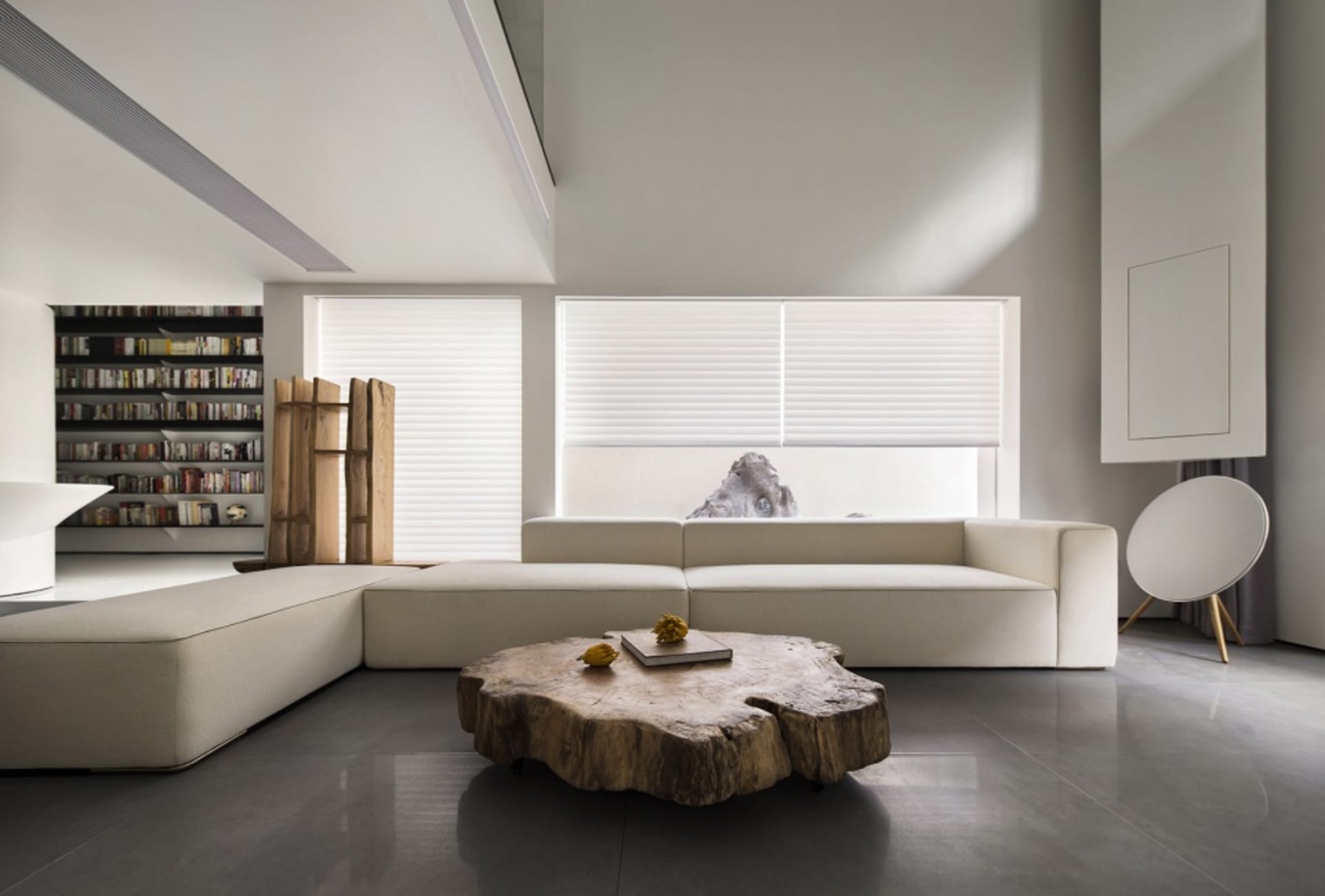 A minimalist living room featuring a white sectional sofa, wooden coffee table, and concrete floor.