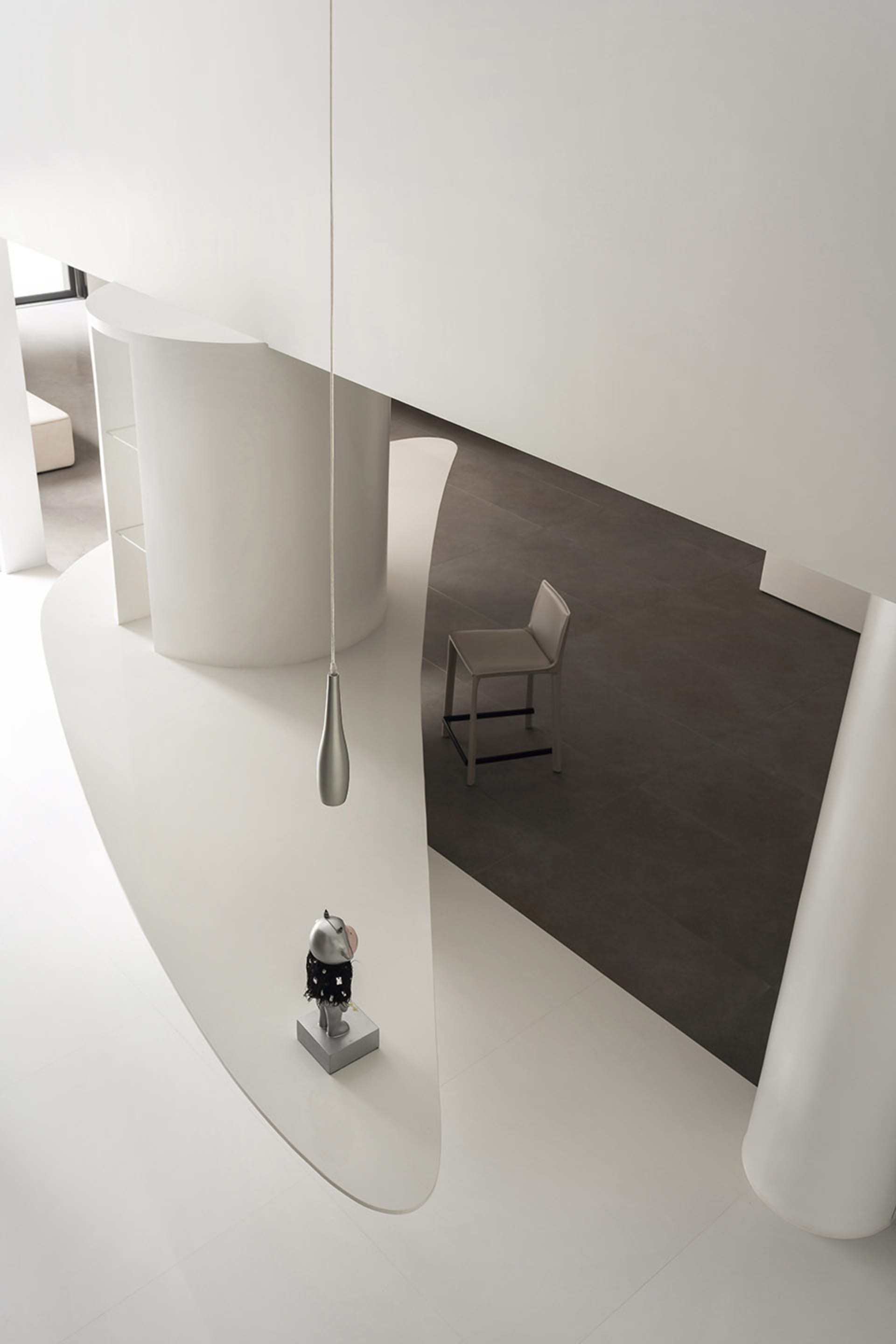 A minimalist modern interior design featuring clean white concrete surfaces and sleek stainless steel elements.