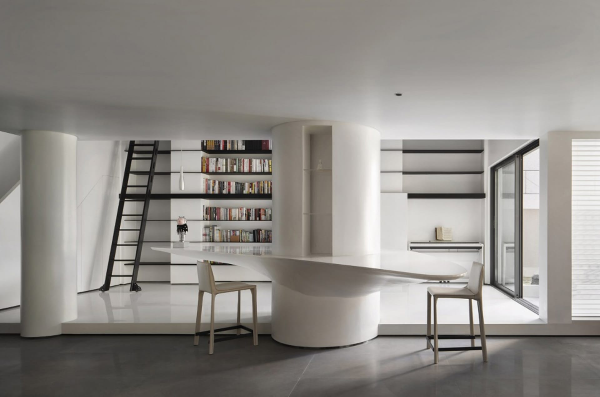 A modern library with a concrete floor and minimalist design, featuring a curved desk and bookshelves.