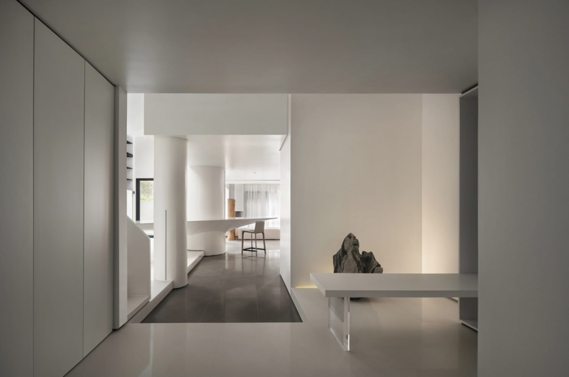 A minimalist interior design in white and black, featuring a concrete floor and walls with a single, modern table.