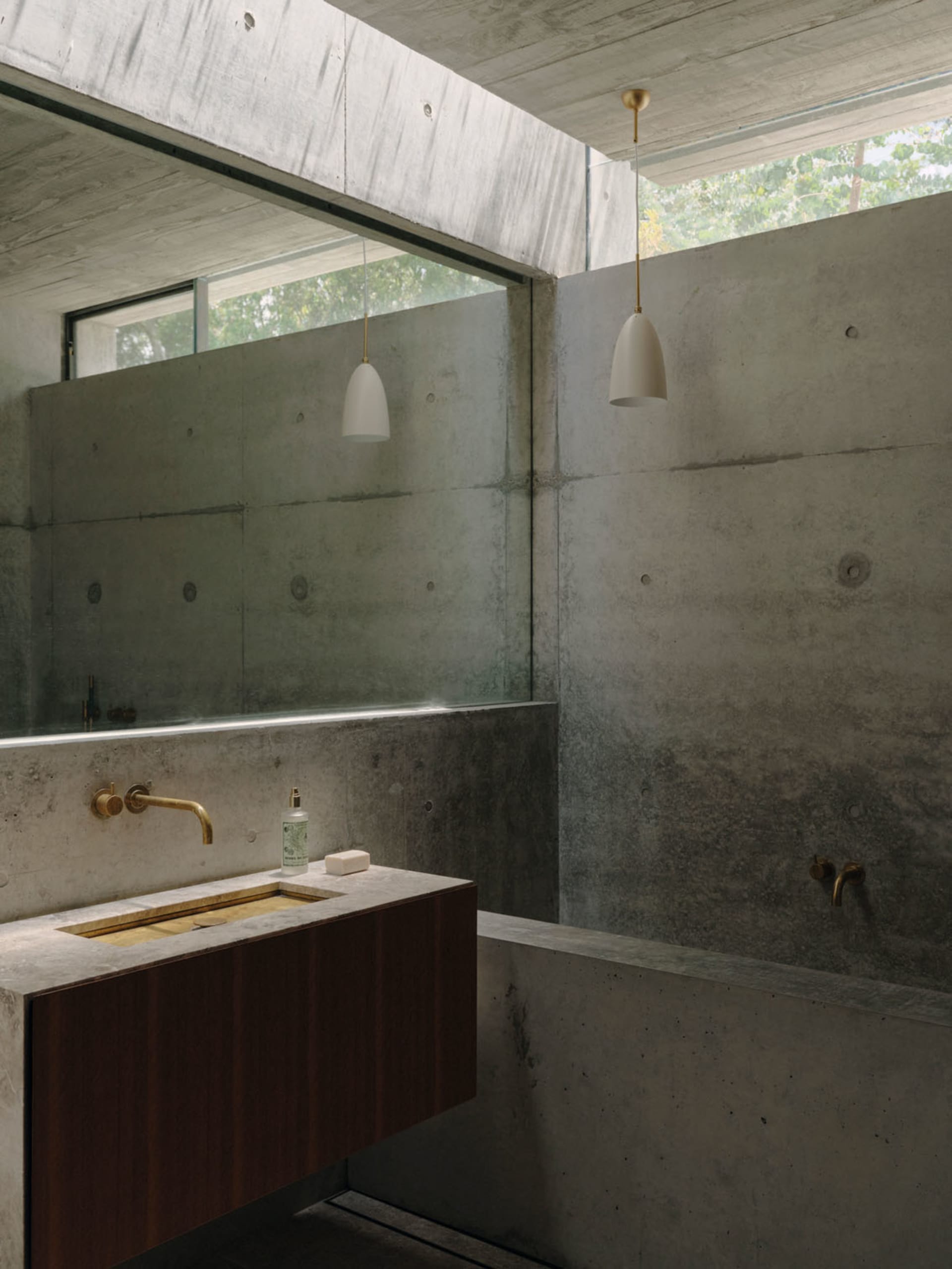 Industrial-style bathroom with concrete walls and floor, featuring a minimalist sink and metal fixtures.