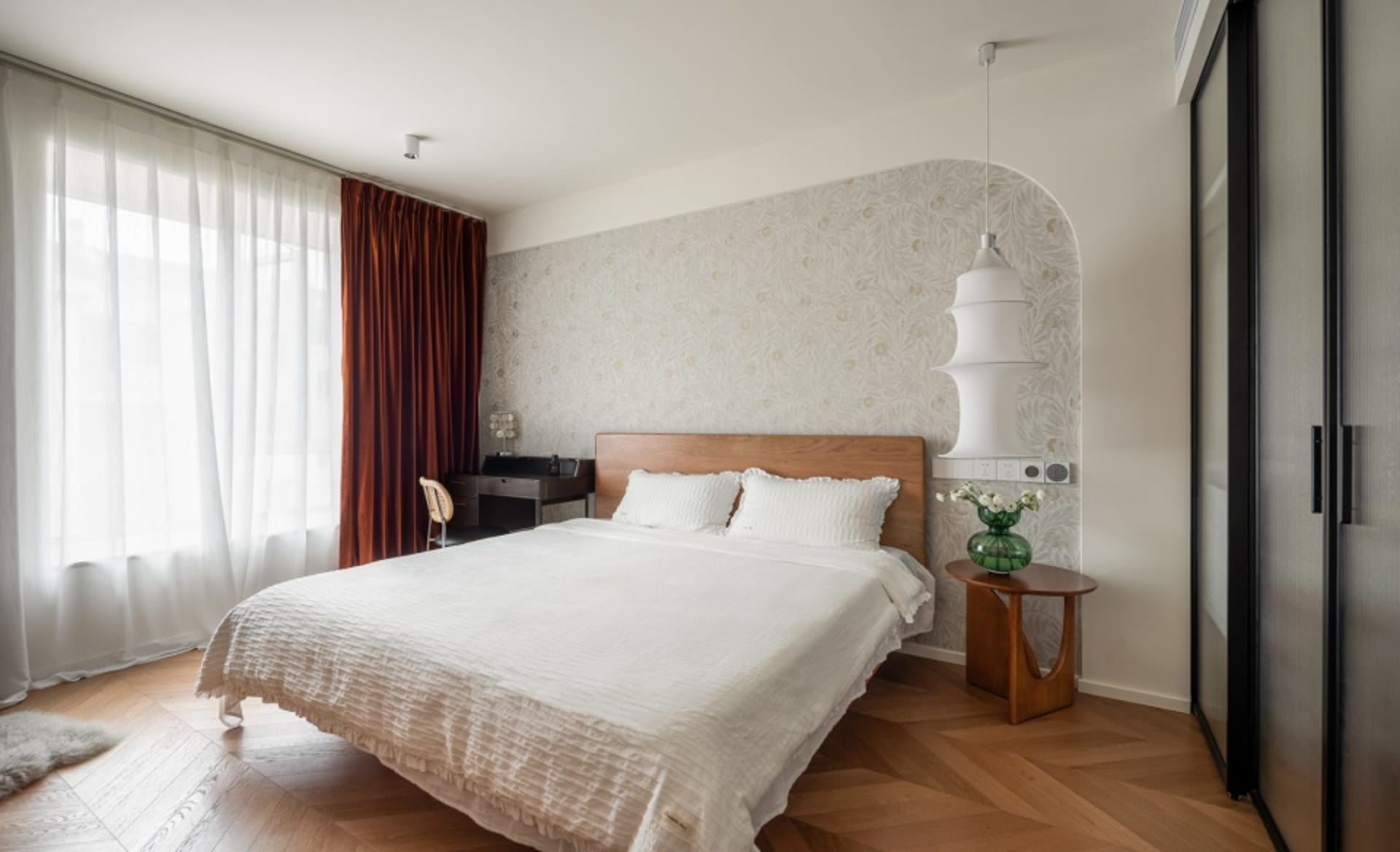 A minimalist bedroom with a white bed, wood headboard, and cotton-blend bedding.