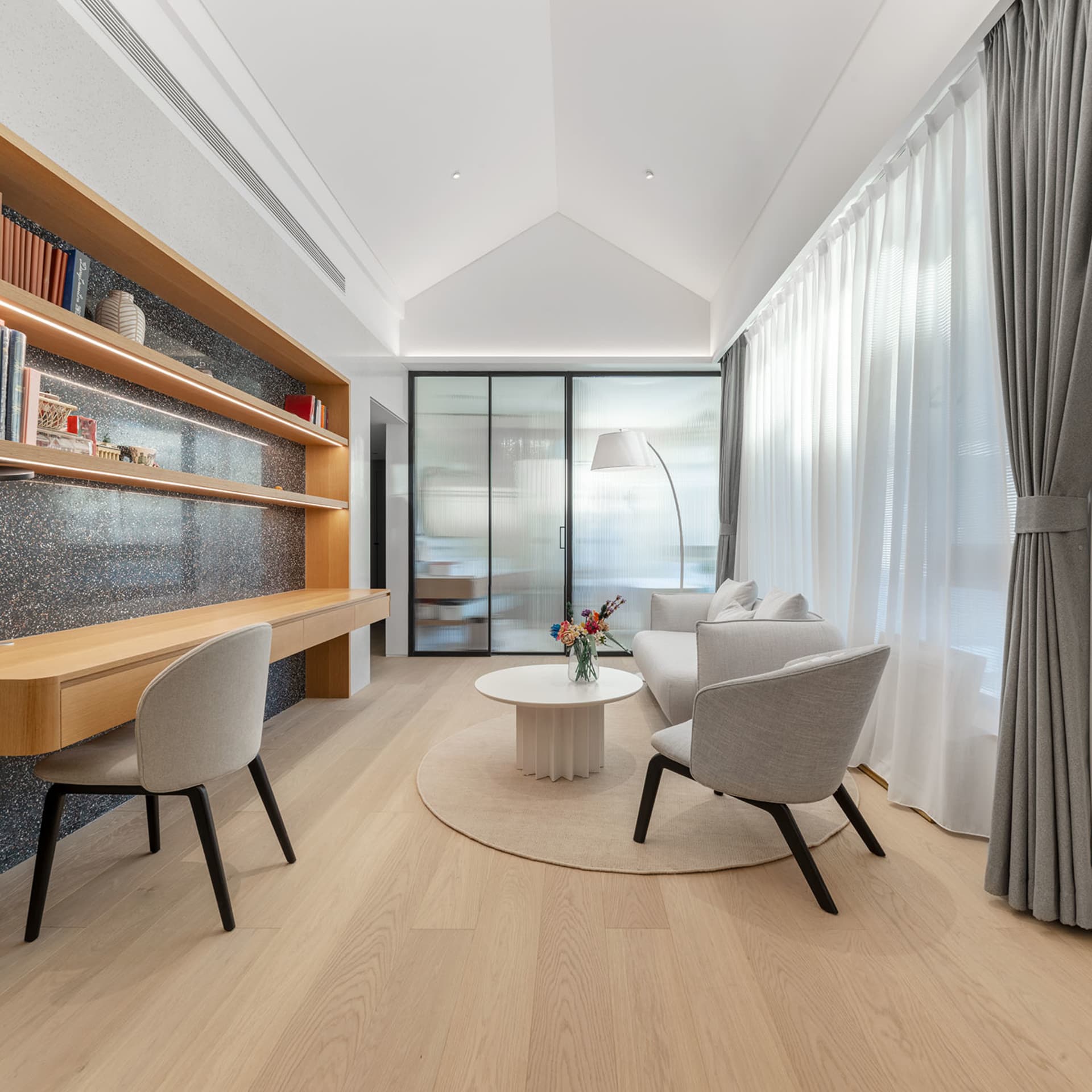 現代簡約客廳，配有白色咖啡桌、灰色扶手椅及木質地板。