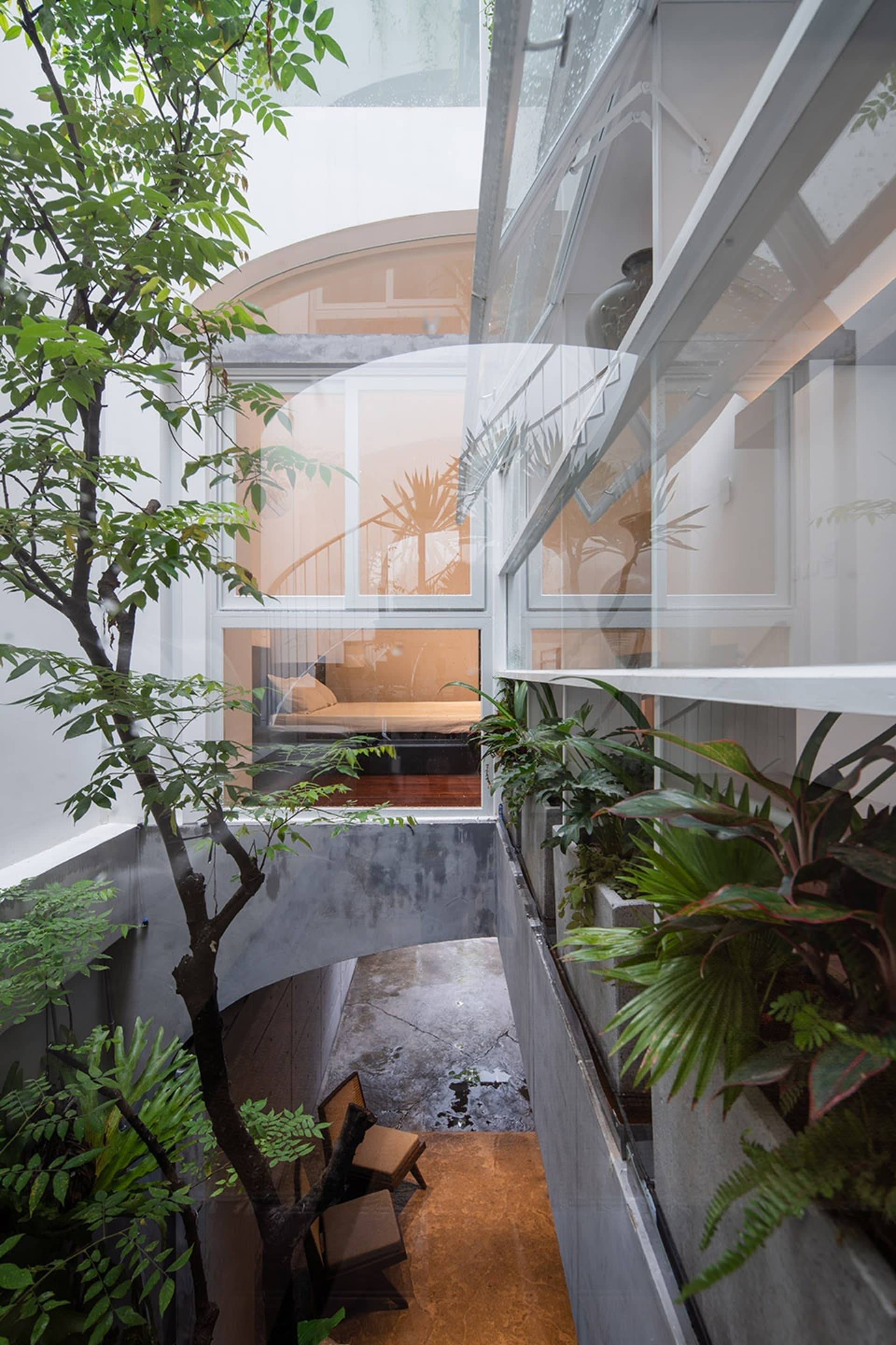 Modern interior courtyard with concrete walls, glass railings, and tropical plants