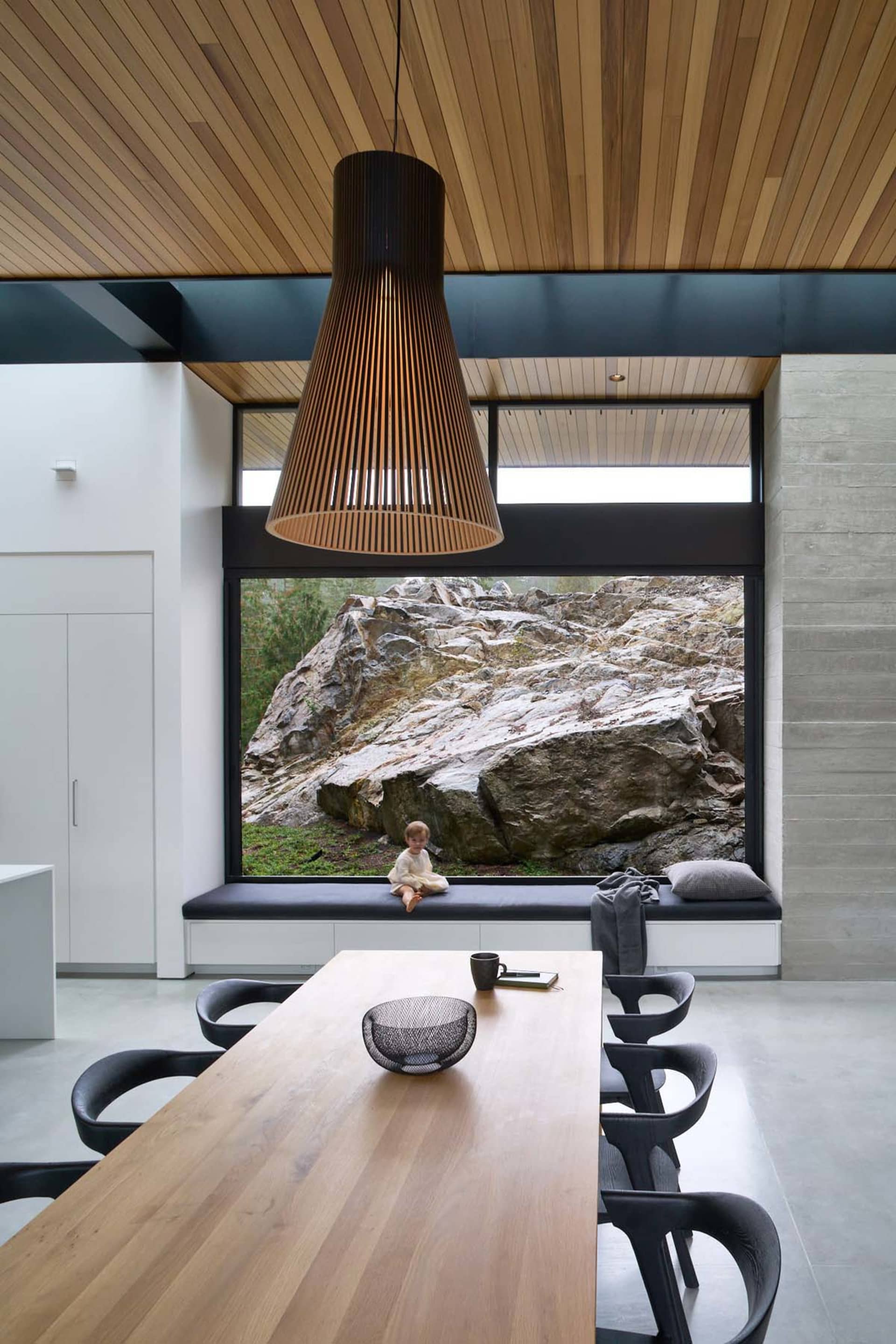 現代餐廳內設有木質餐桌與座位區，大型窗戶可眺望戶外岩石與自然景色。