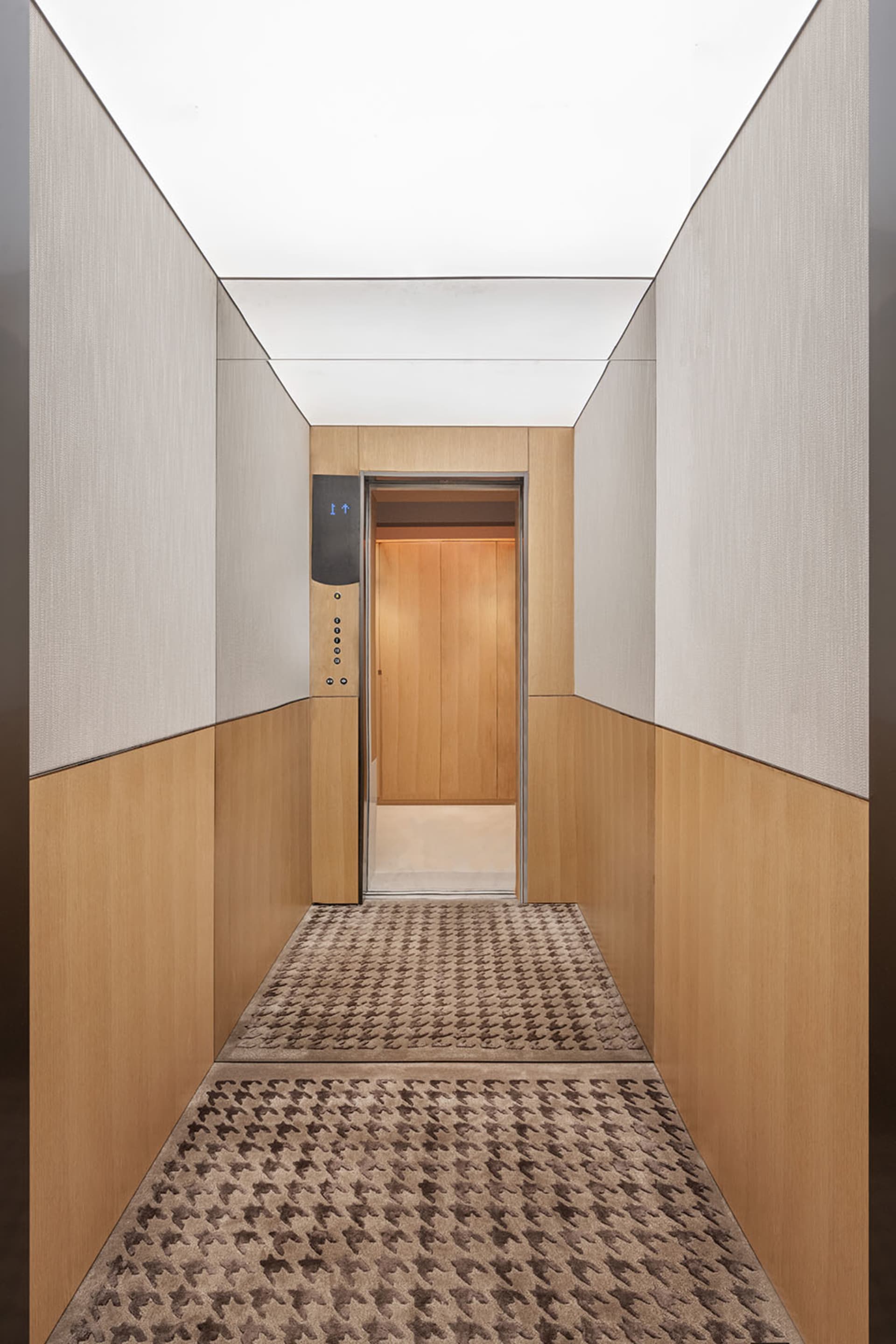 Modern elevator interior with wooden panels and a patterned carpet