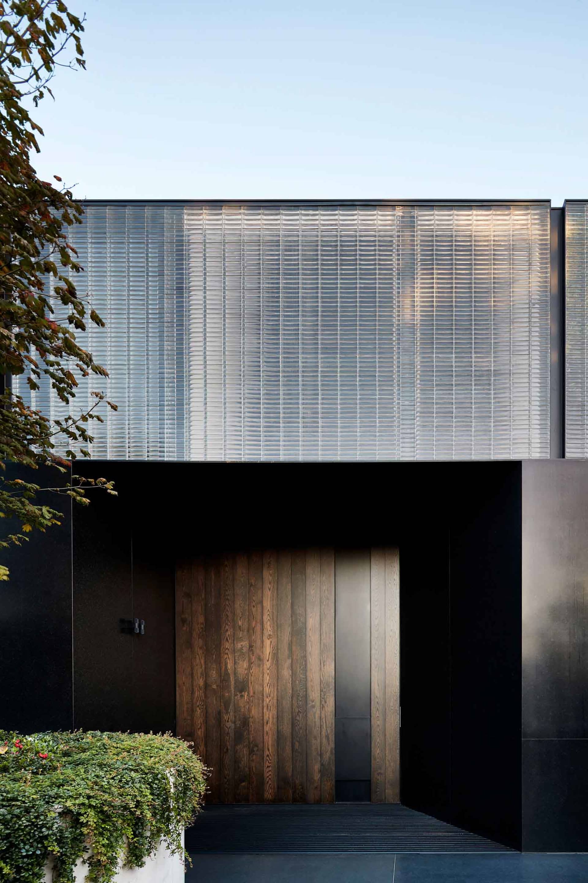 Modern residential home with a large glass wall and wooden door.