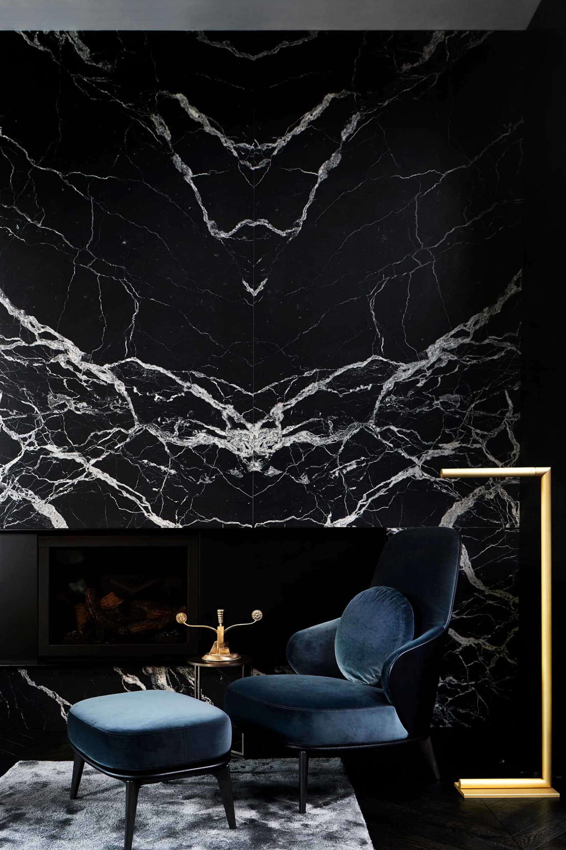 Modern living room featuring black marble accent wall and navy blue armchair