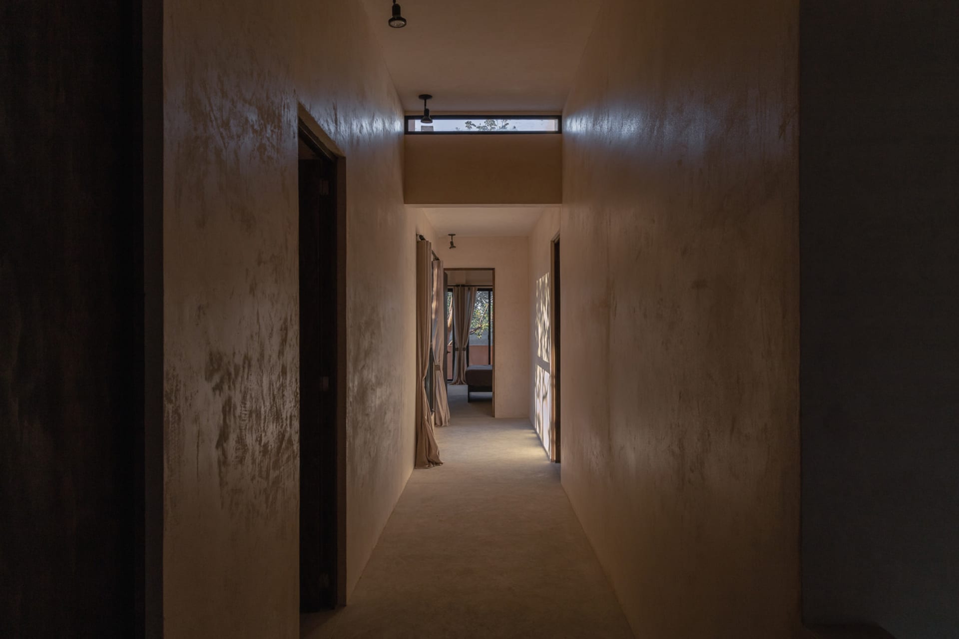 An empty minimalist hallway with concrete walls and a long, light-filled corridor.