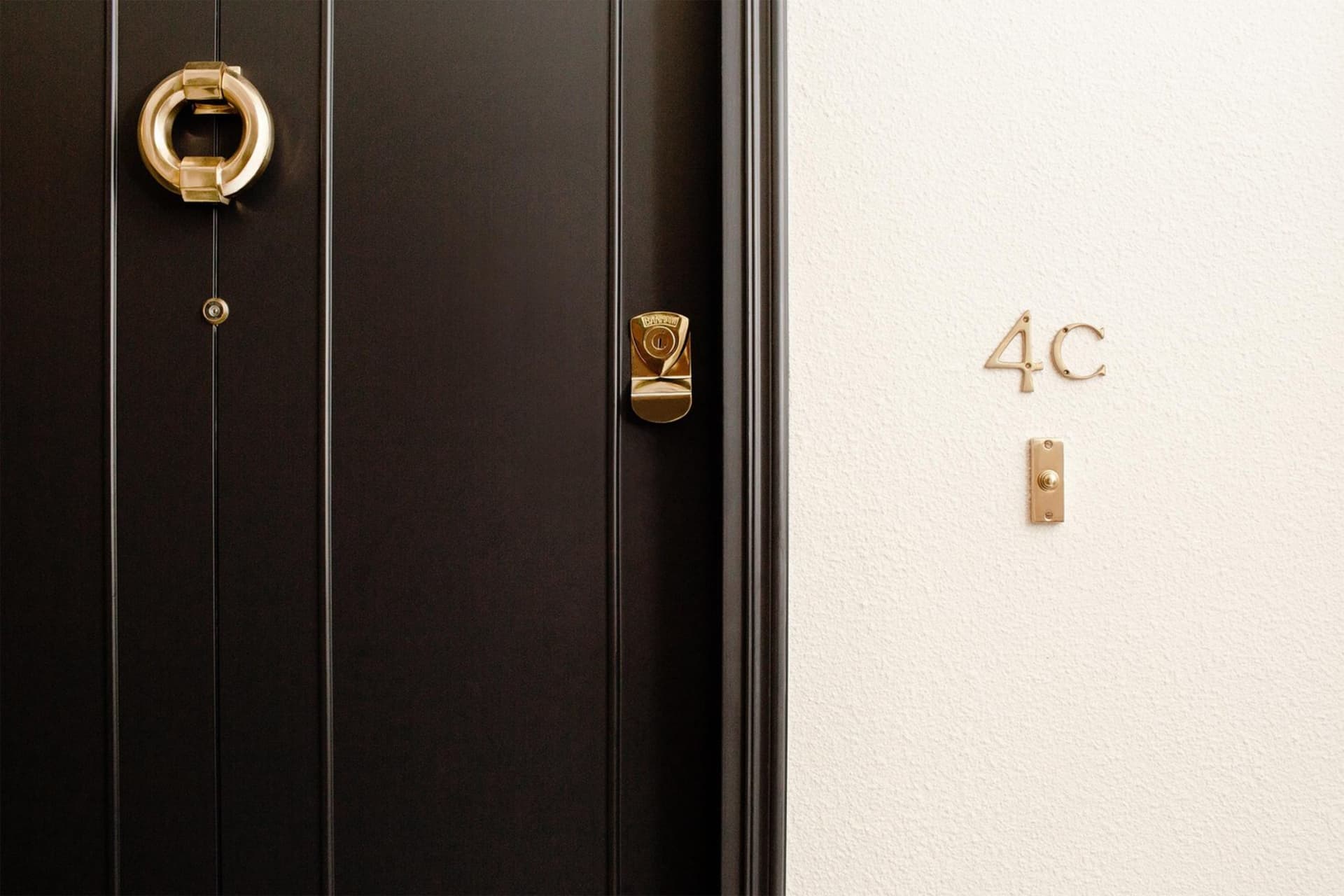 A modern black door with a golden brass handle and lock.