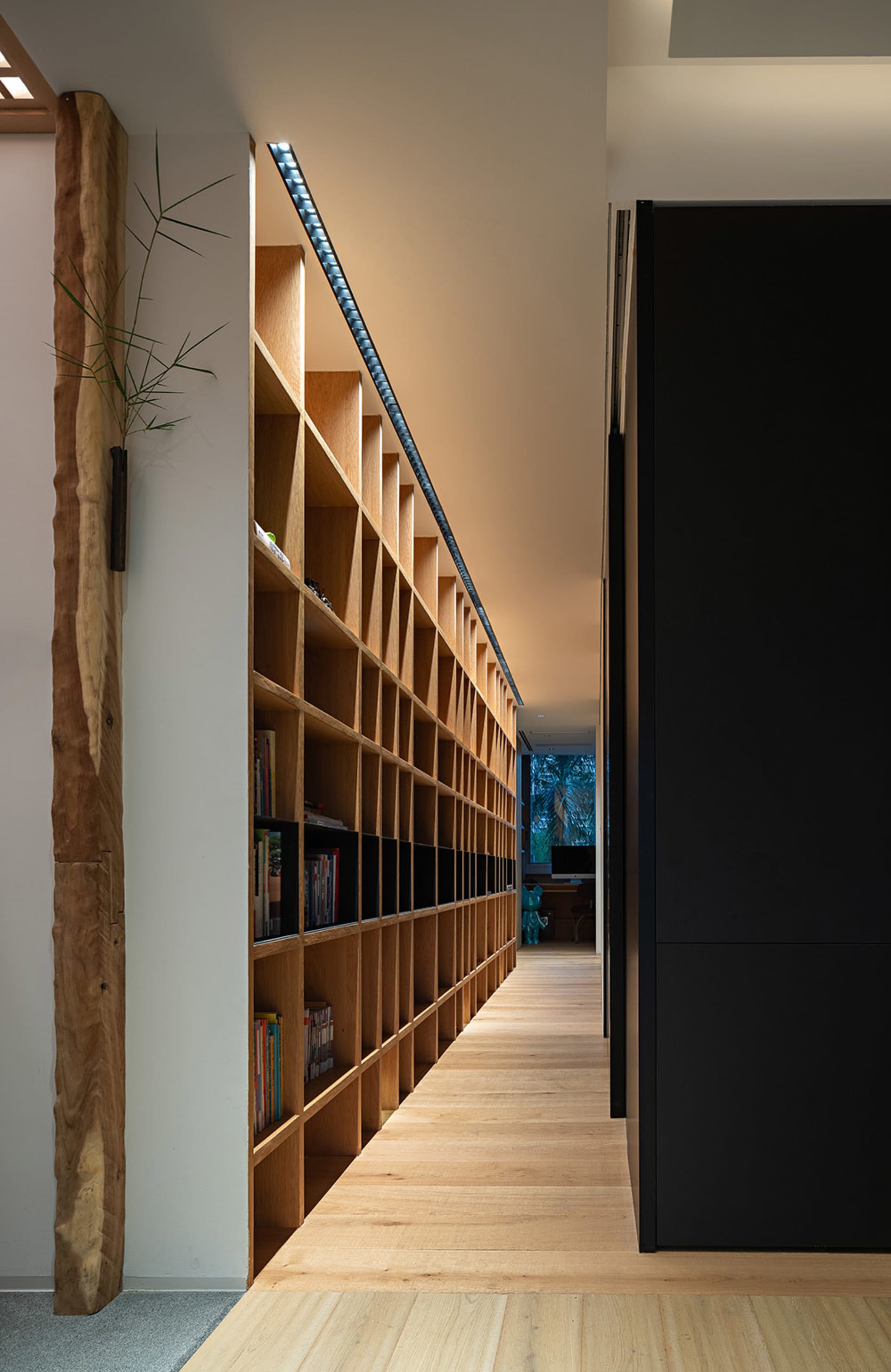A modern industrial library with wooden shelves filled with books and plants.