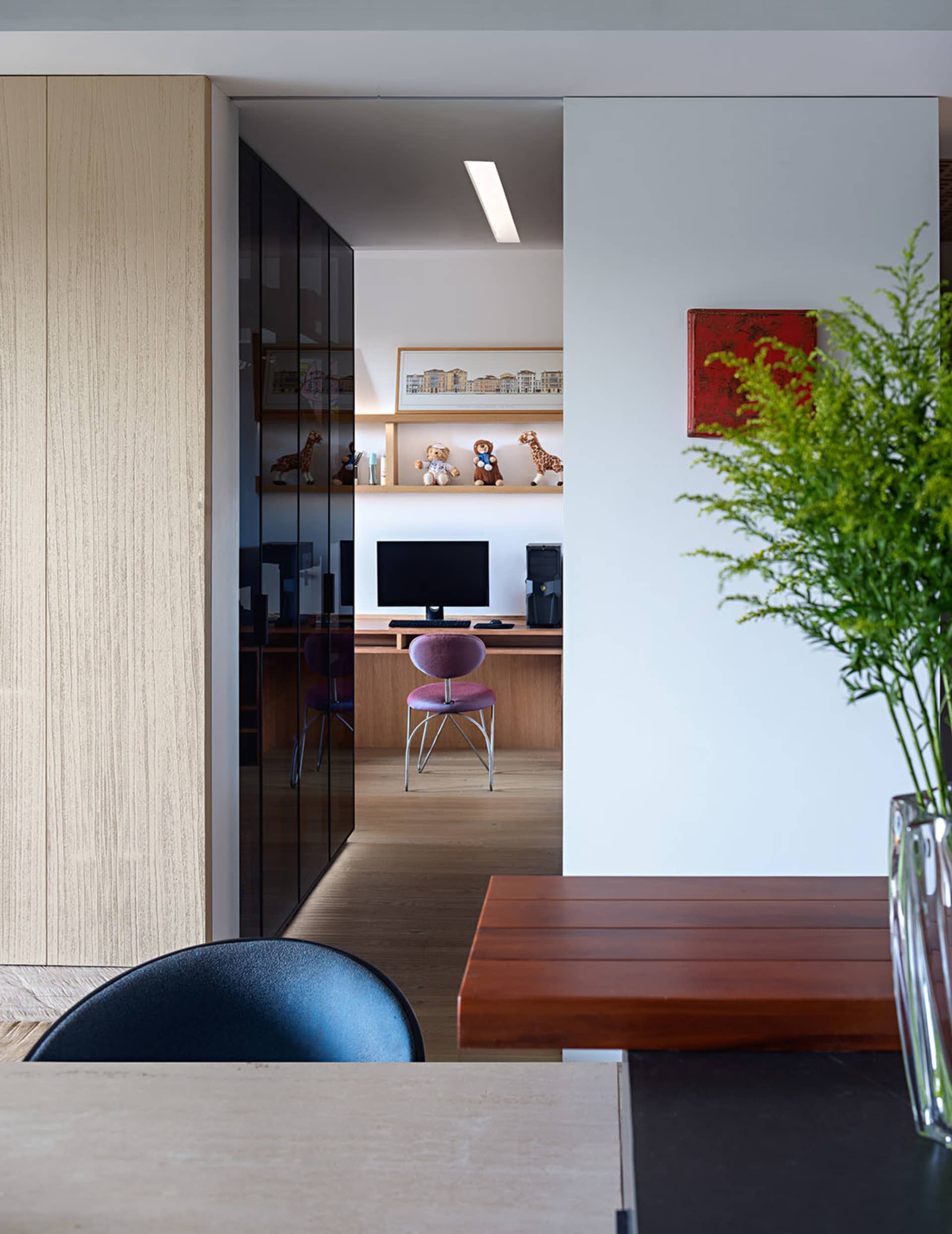 A modern office space with wooden furniture, featuring a desk, chair, and computer setup.