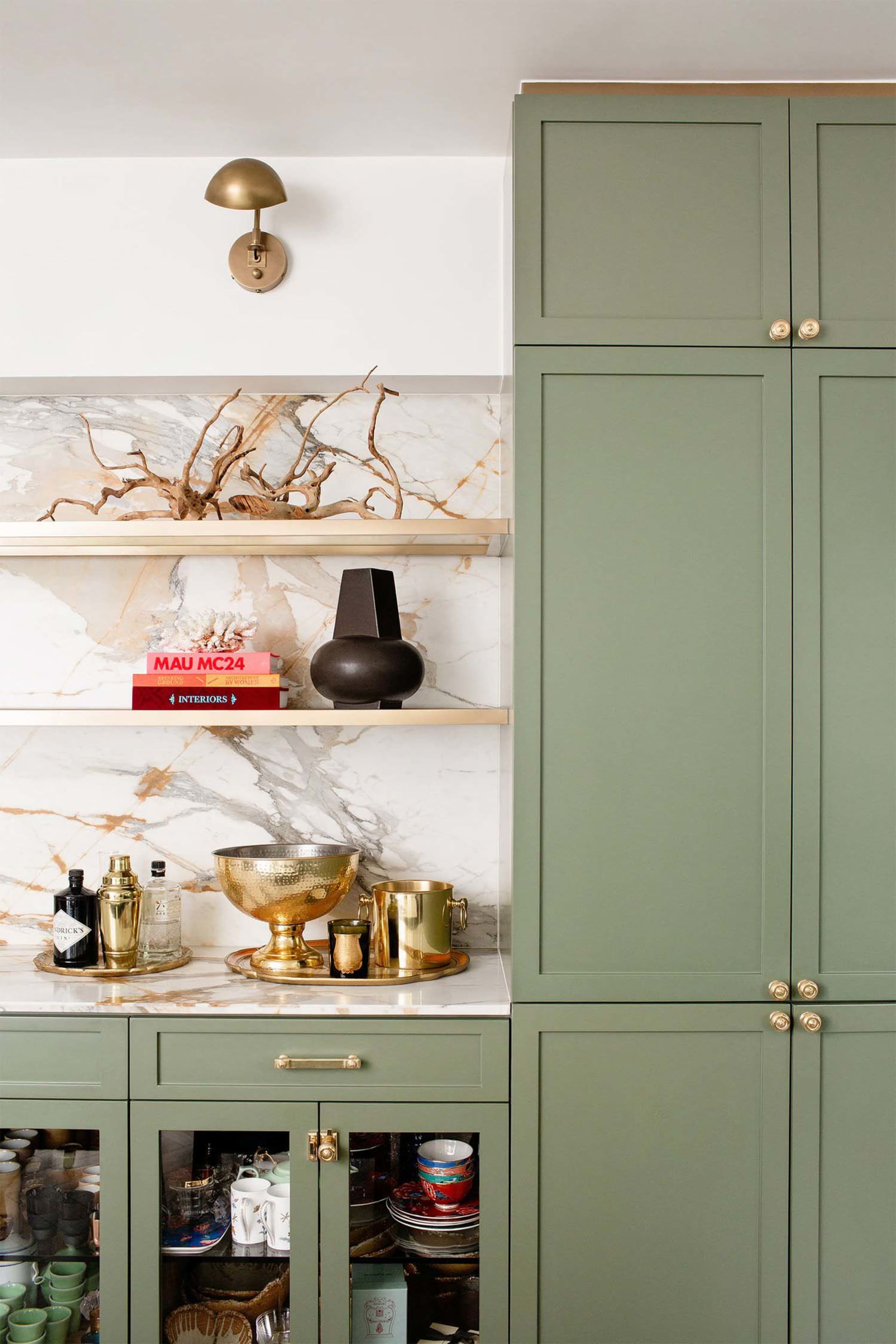 A modern green kitchen with marble countertops and brass accents.