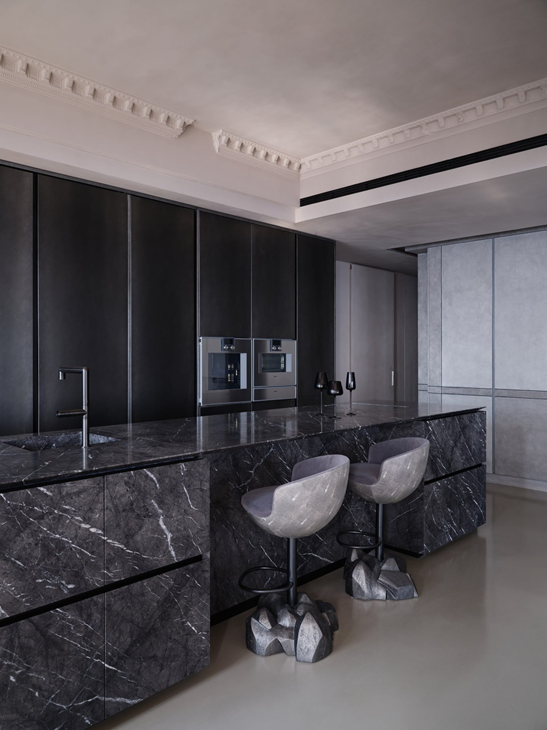 Modern kitchen with marble countertops, black cabinetry, and minimalist design.
