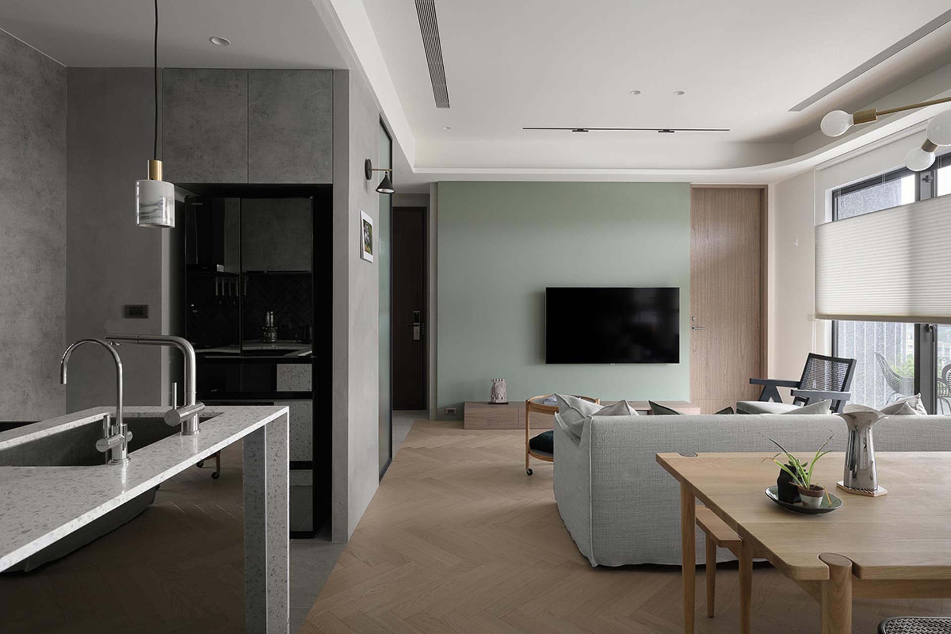 A modern living room featuring concrete walls, wooden flooring, and fabric couches.