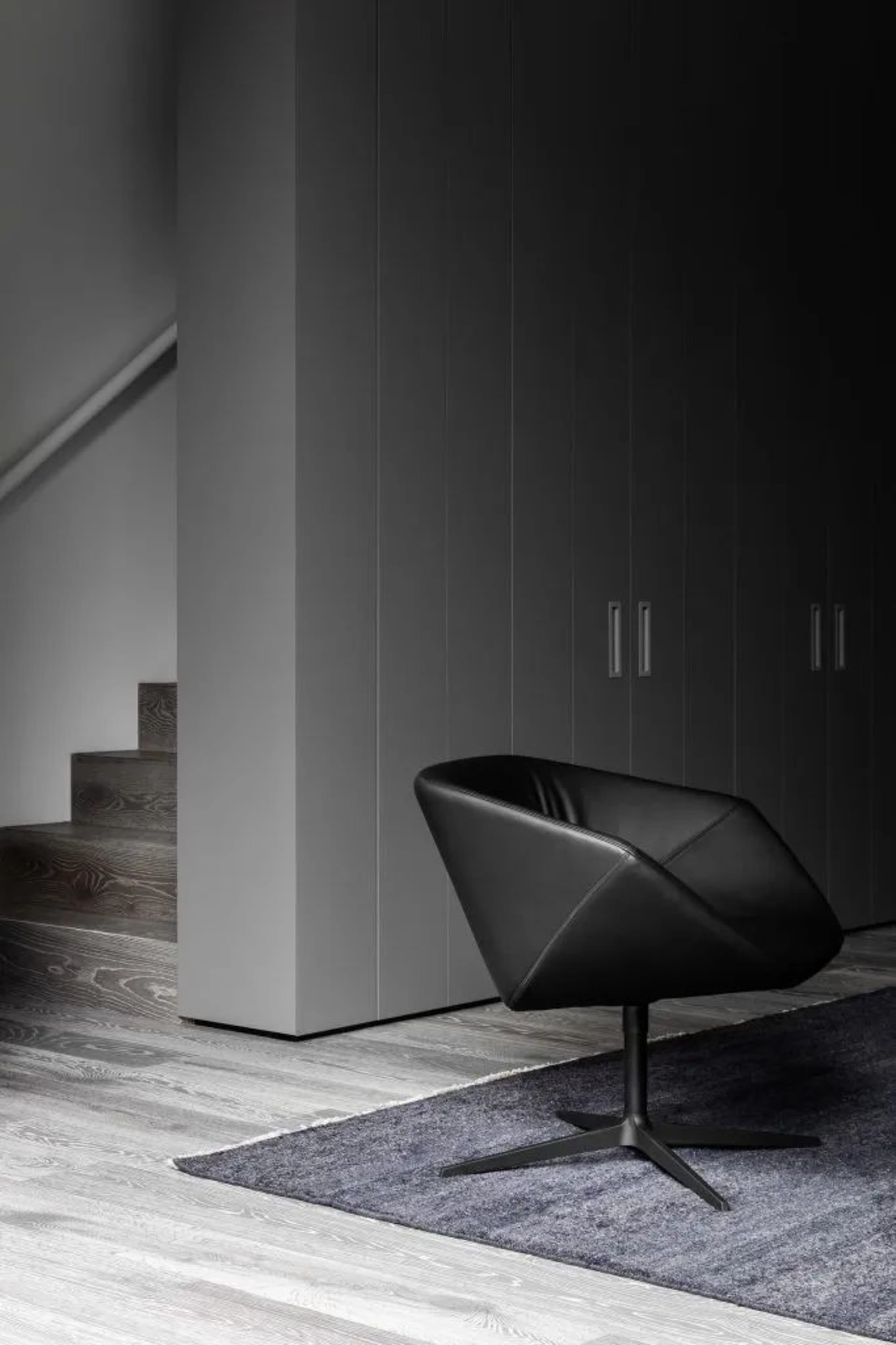 A black leather swivel chair with metallic legs in an industrial living space.