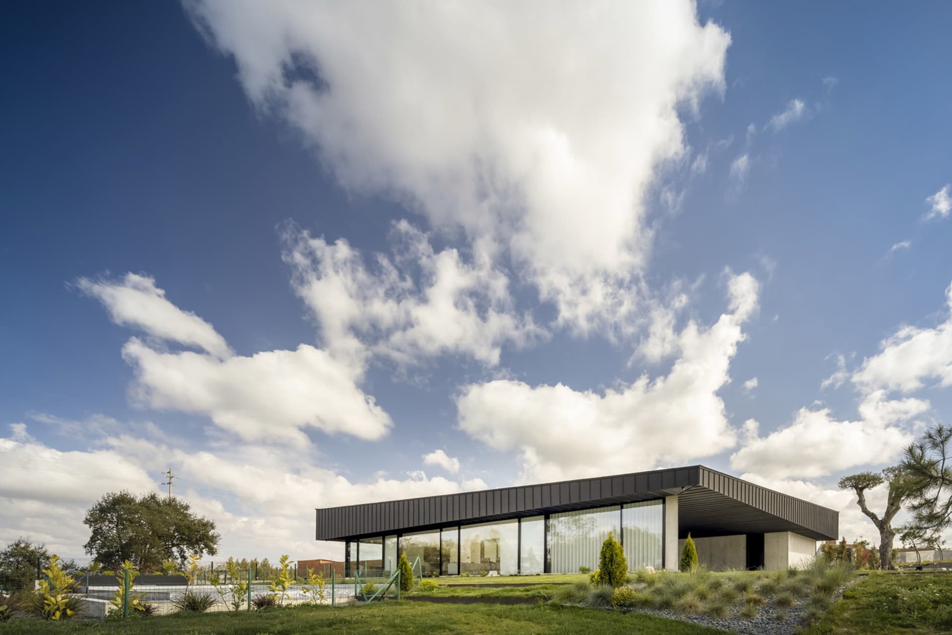 A modern building with a glass and steel exterior under a blue sky with clouds.