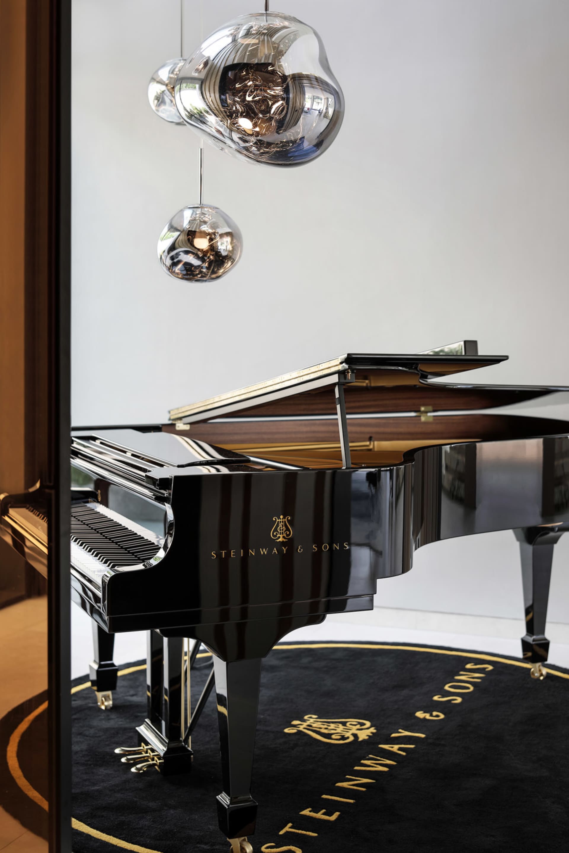現代音樂室內擺放一台黑色 Steinway & Sons 鋼琴，並搭配當代吊燈。