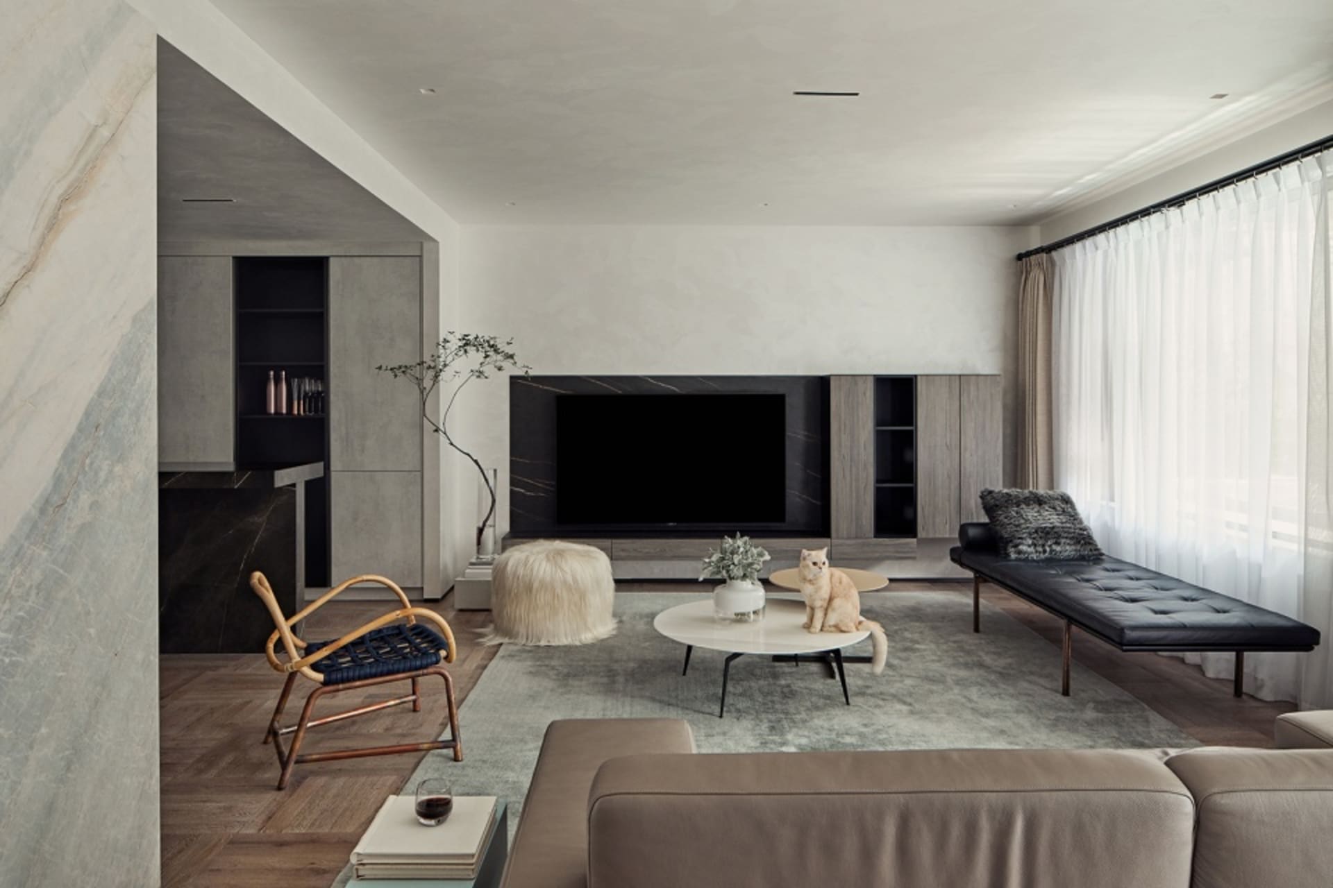 A living room with a modern minimalist design featuring a large sofa, coffee table, and television unit.