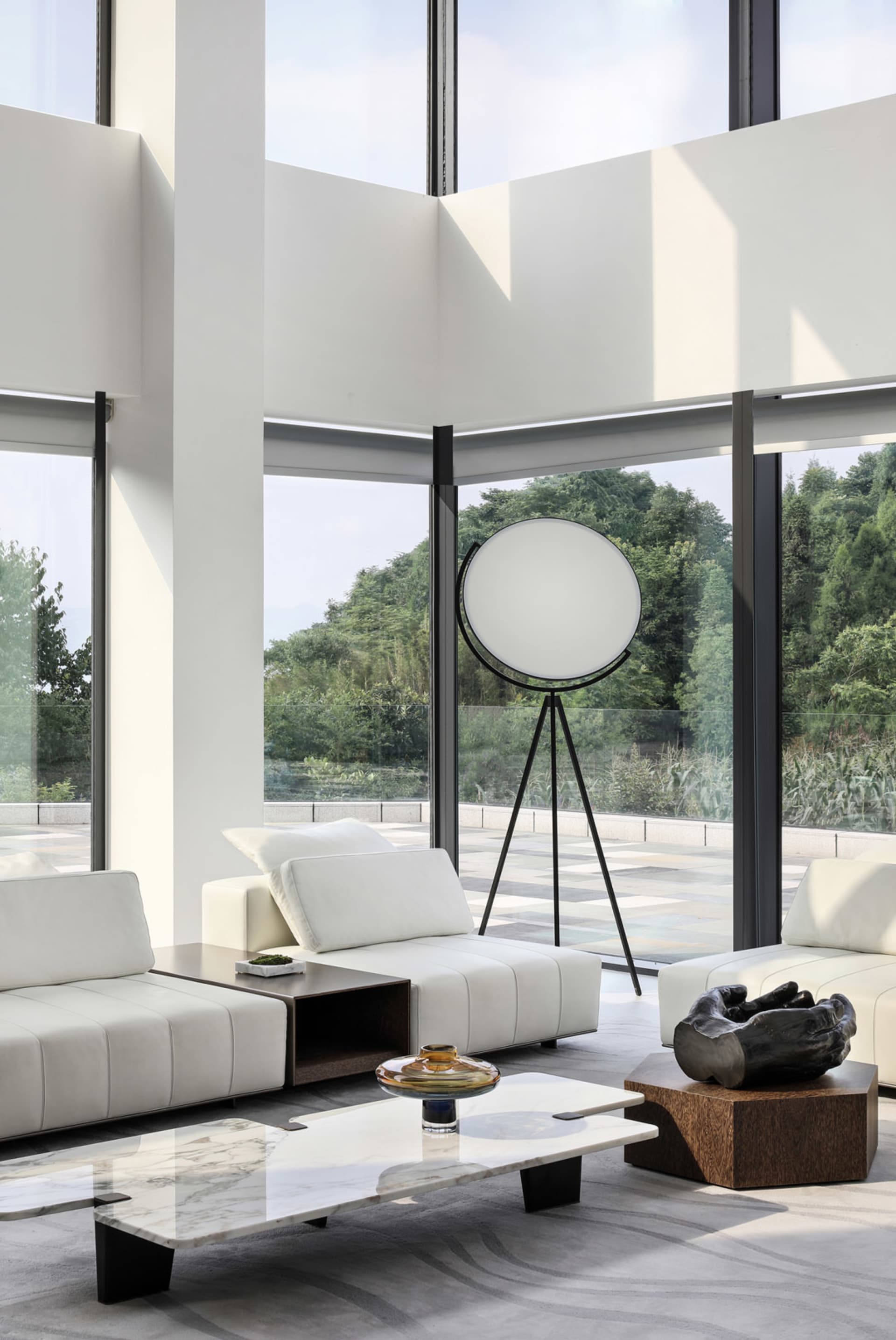 Modern white leather furniture with marble coffee table and large floor lamp in a spacious living room with floor-to-ceiling