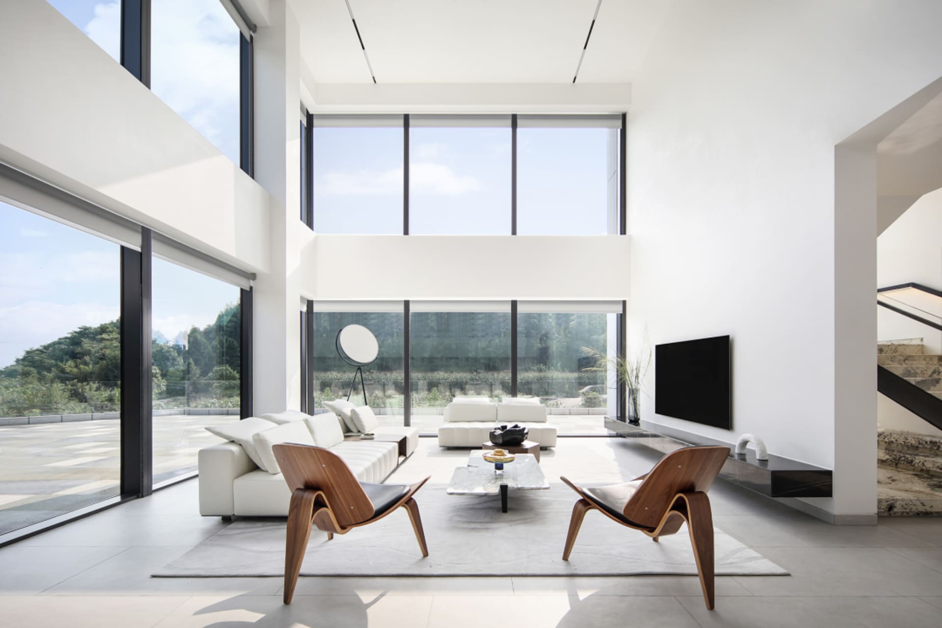 A spacious modern living room featuring minimalist decor and steel and glass elements.