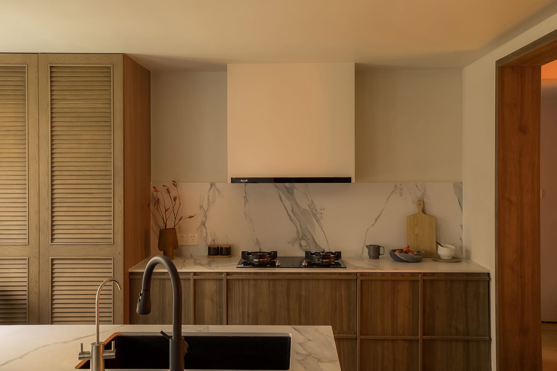 Modern residential kitchen featuring marble countertops and wooden cabinetry, with a minimalist design.