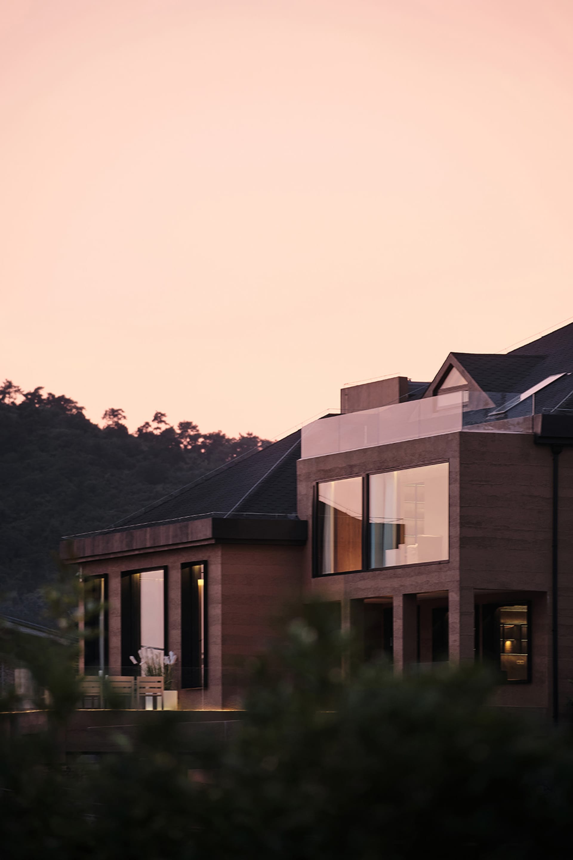 一座採用玻璃、木質與金屬材質的現代住宅建築。