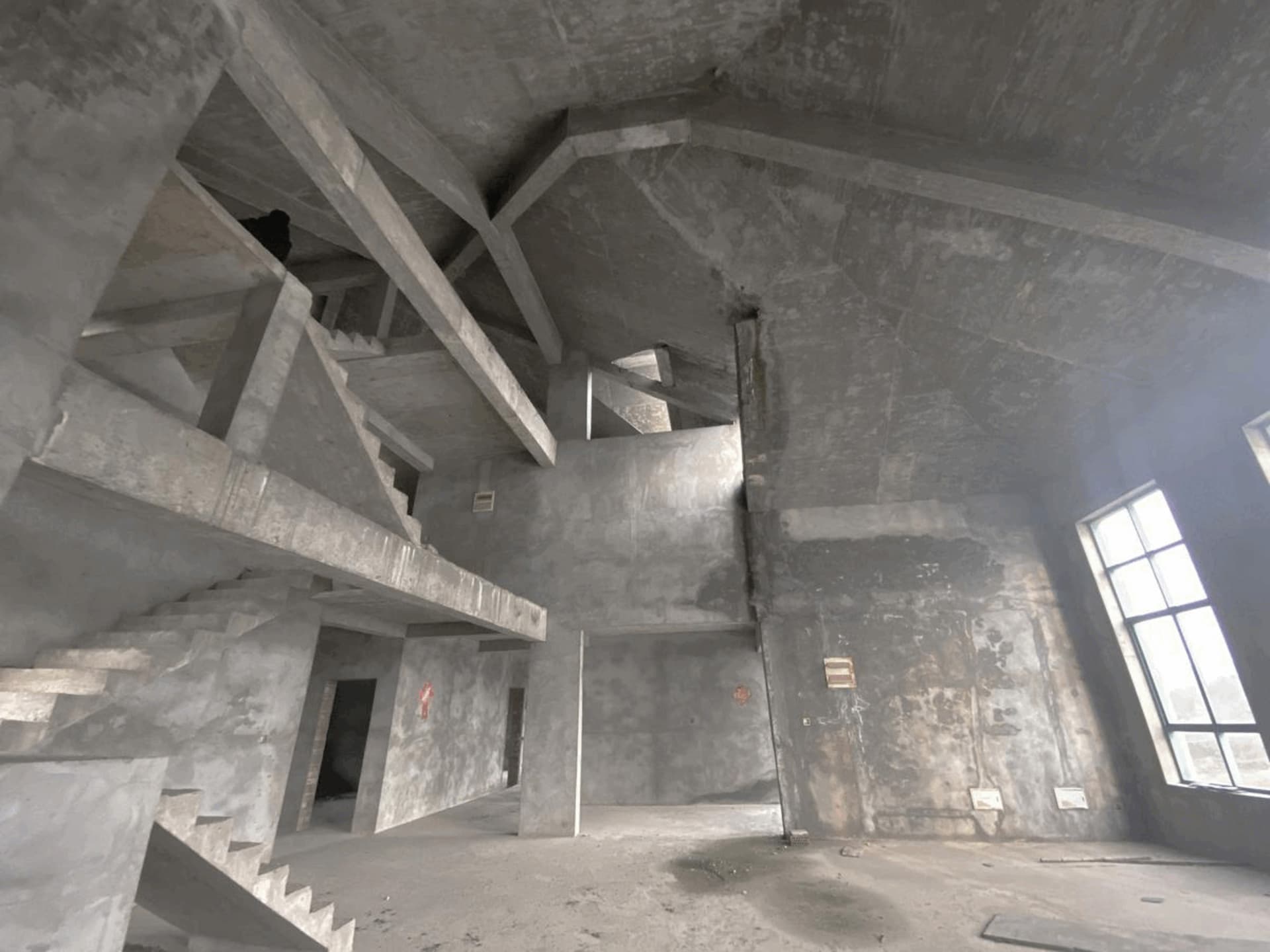 建築物施工或翻修中的未完工室內空間,擁有混凝土牆面與樓梯。