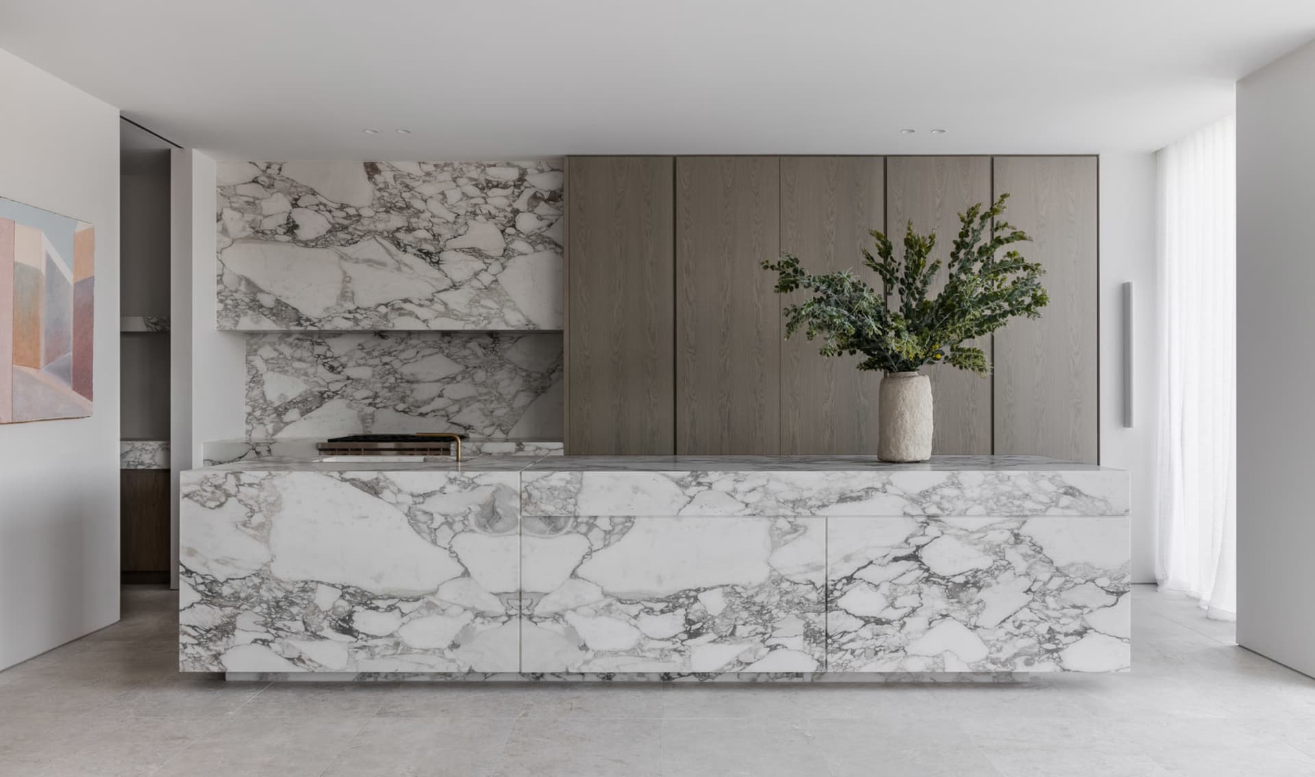 A modern minimalist kitchen featuring marble countertops and cabinets.