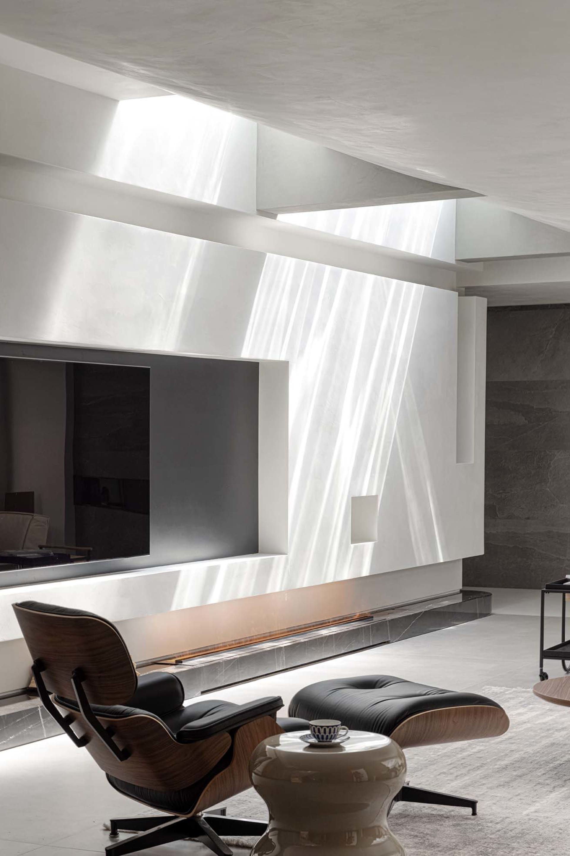 A modern living room featuring a concrete wall, wooden accents, and glass elements.