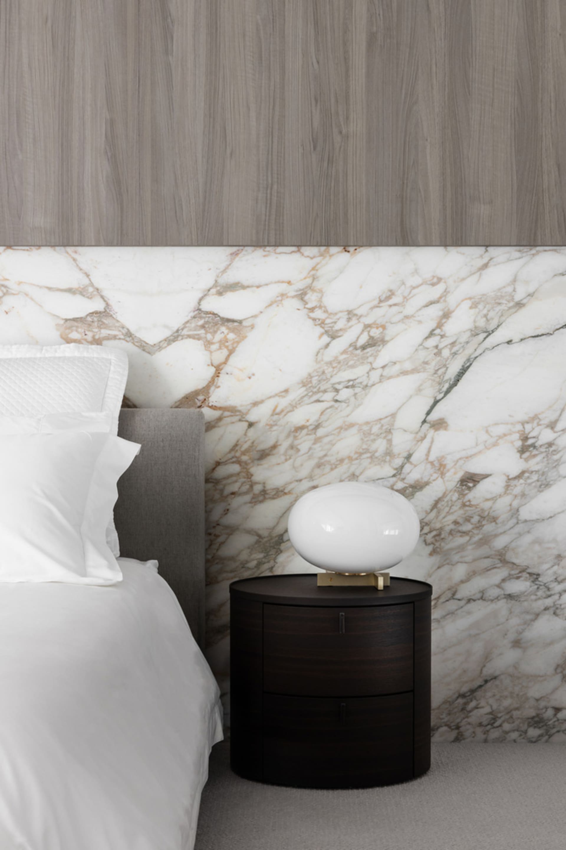 極簡臥室，配有灰色絨布床頭板與白色大理石點綴。