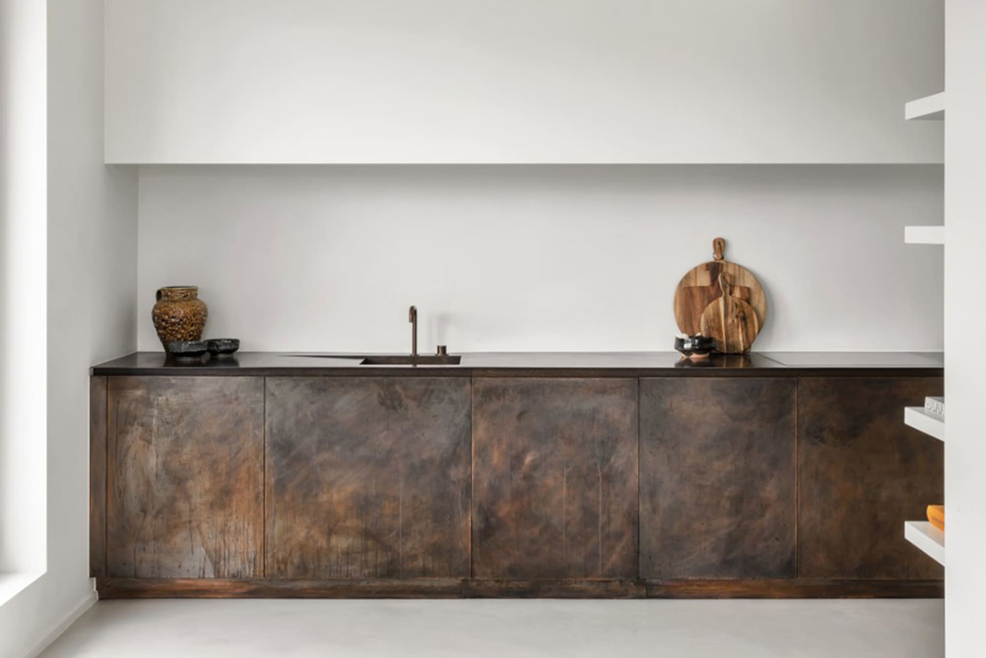 A minimalist kitchen featuring wooden cabinets, a black countertop, and a minimalistic design.