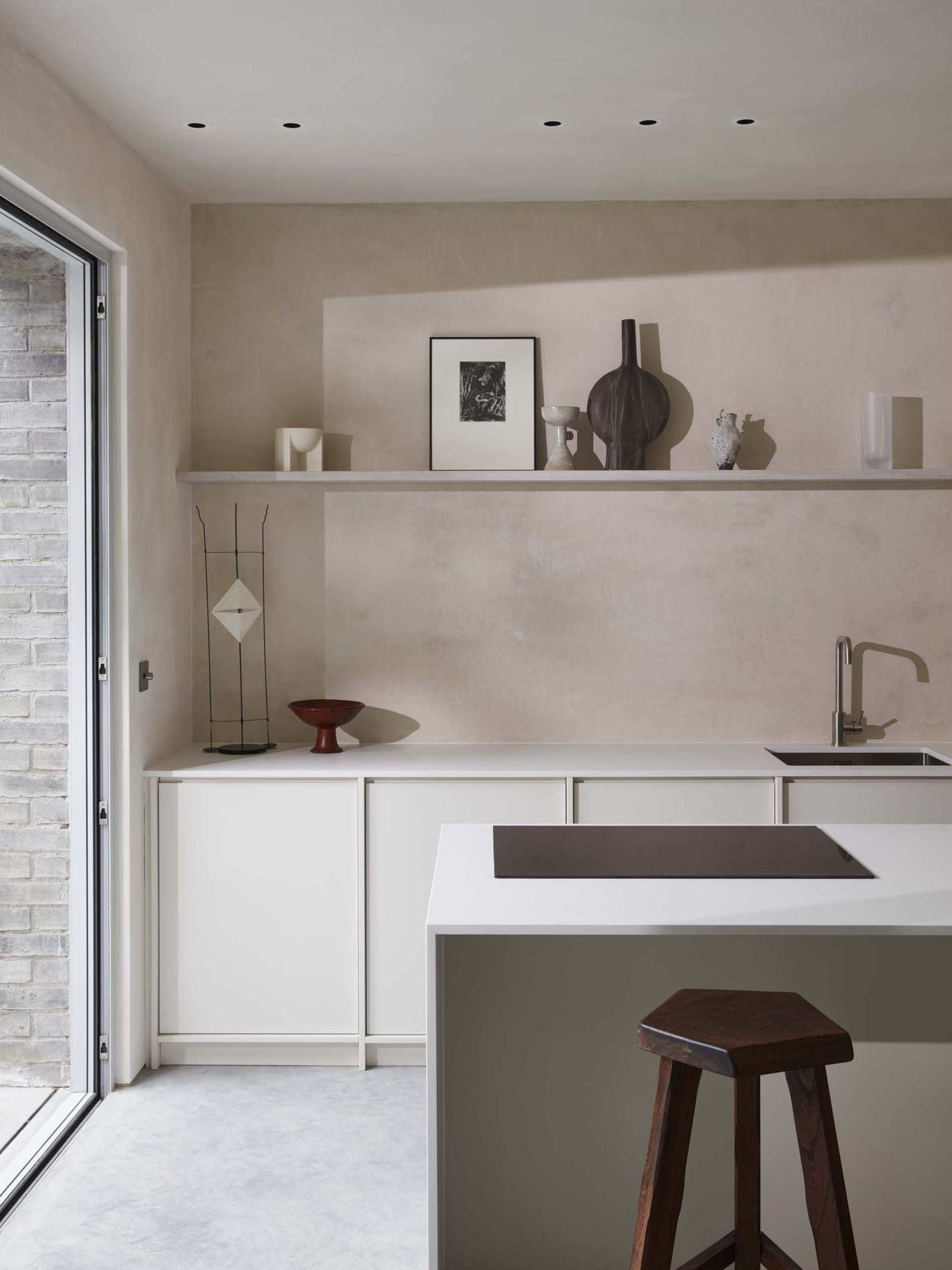 Modern, minimalist residential kitchen with white marble countertops and cabinets, featuring a central island and a sleek, co