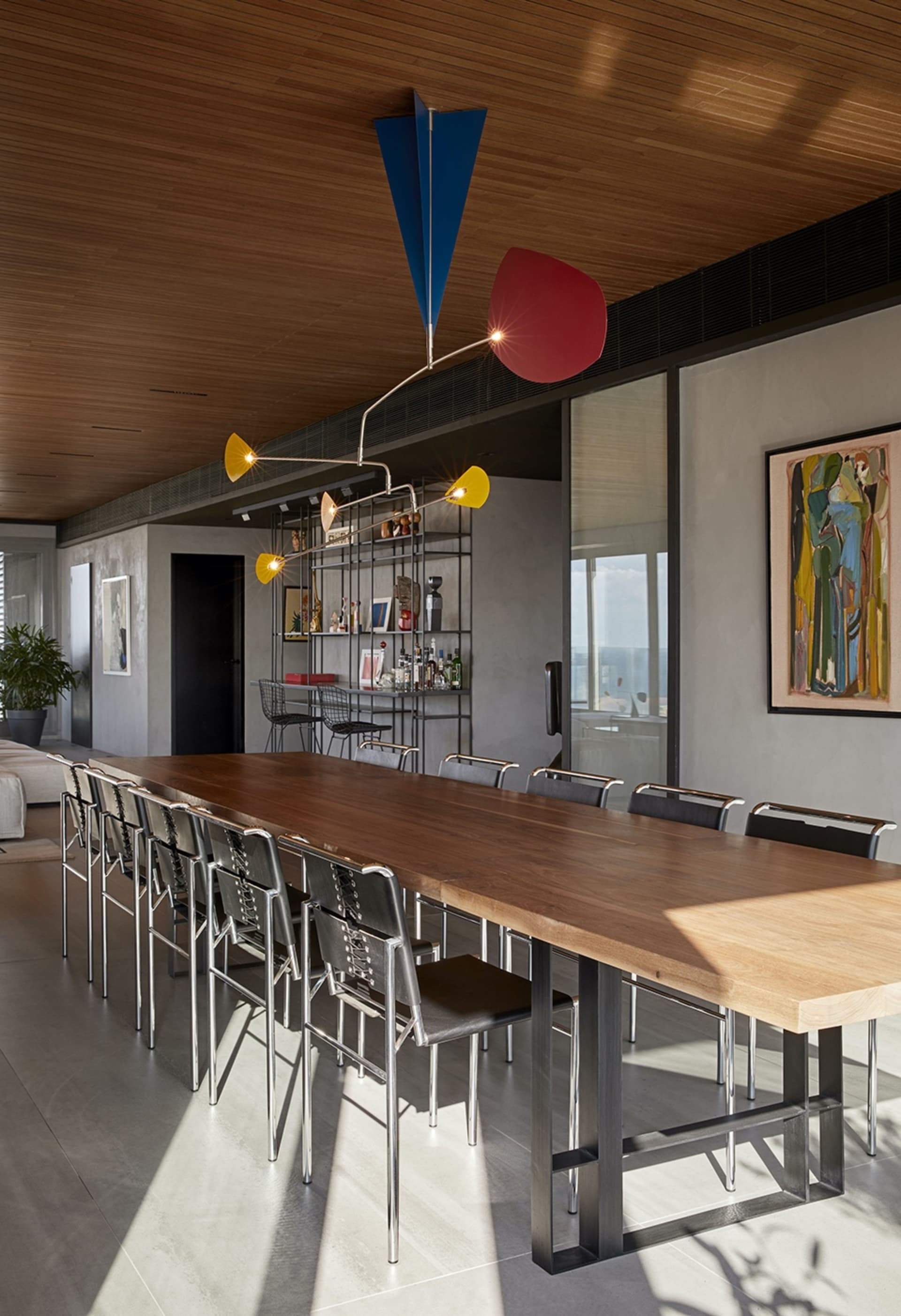 Modern industrial dining room with a long wooden table, metal chairs, and a unique hanging light fixture.