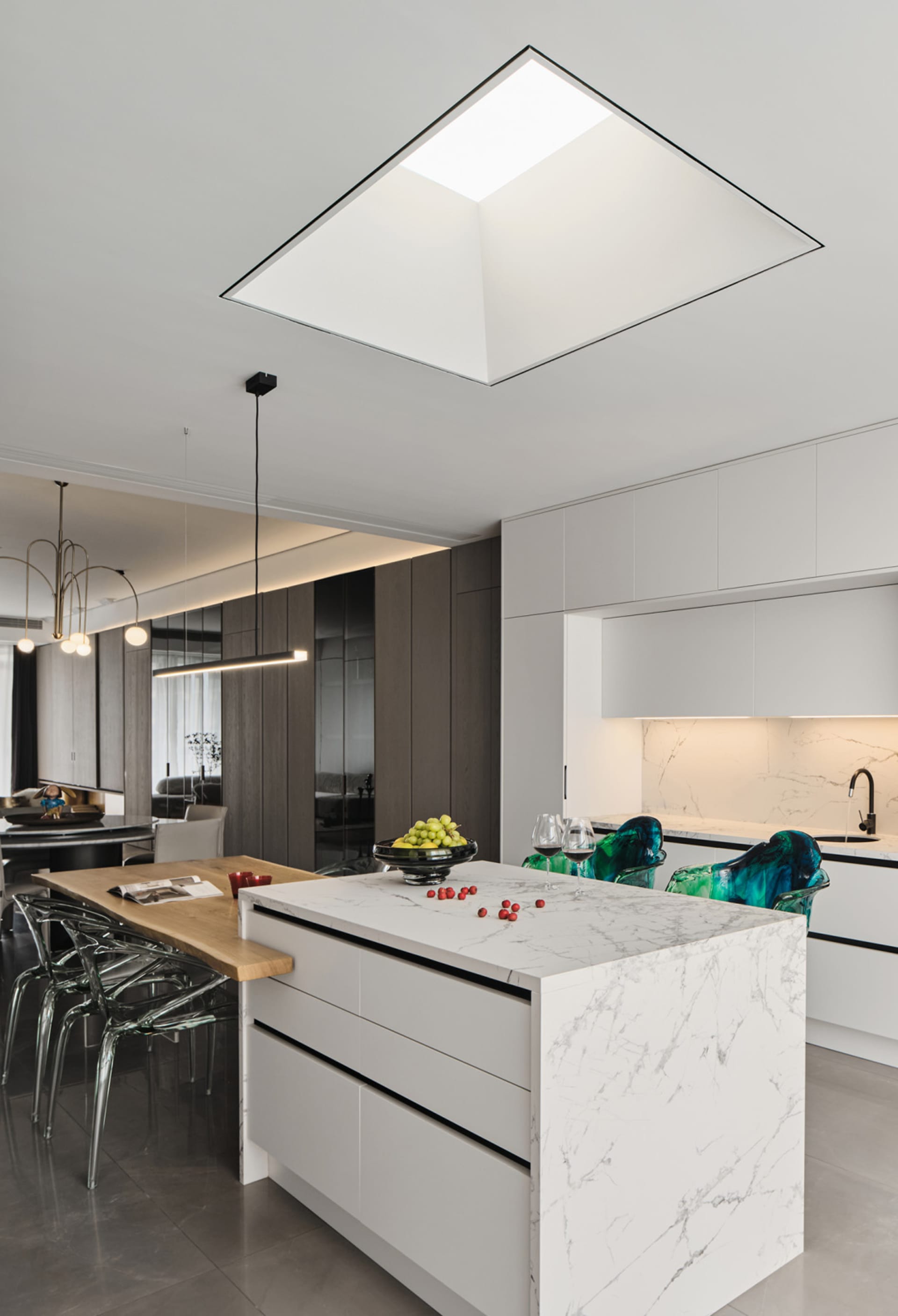 Modern residential kitchen featuring white marble countertops, glass cabinets, and wooden island.