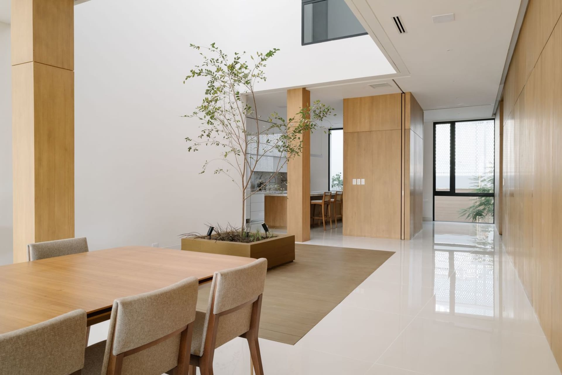 A modern white living room with wooden furniture and large glass windows.